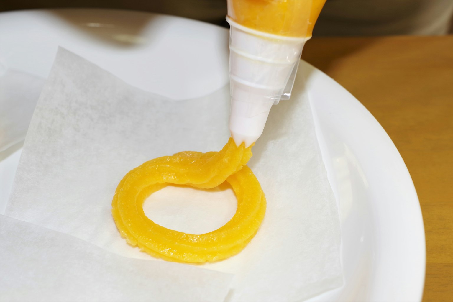 Gelbe Creme wird in Ringform auf einen Teller gespritzt
