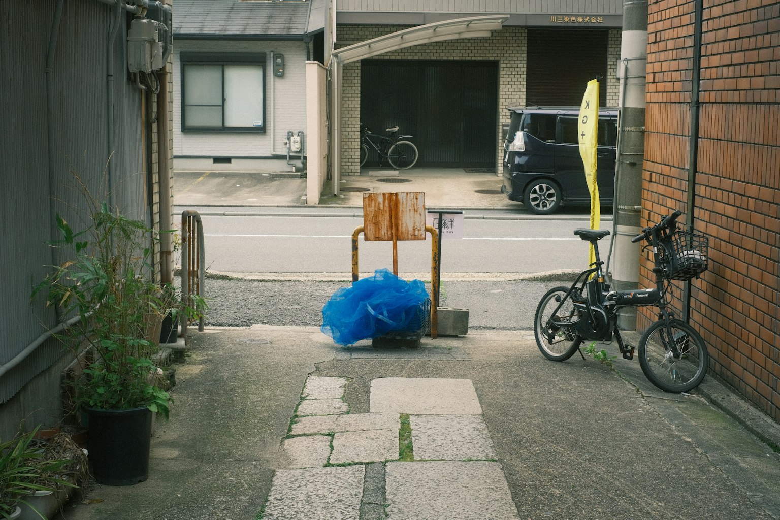 Vista di un vicolo stretto con bicicletta e sacchetto di plastica blu sedia di legno posizionata