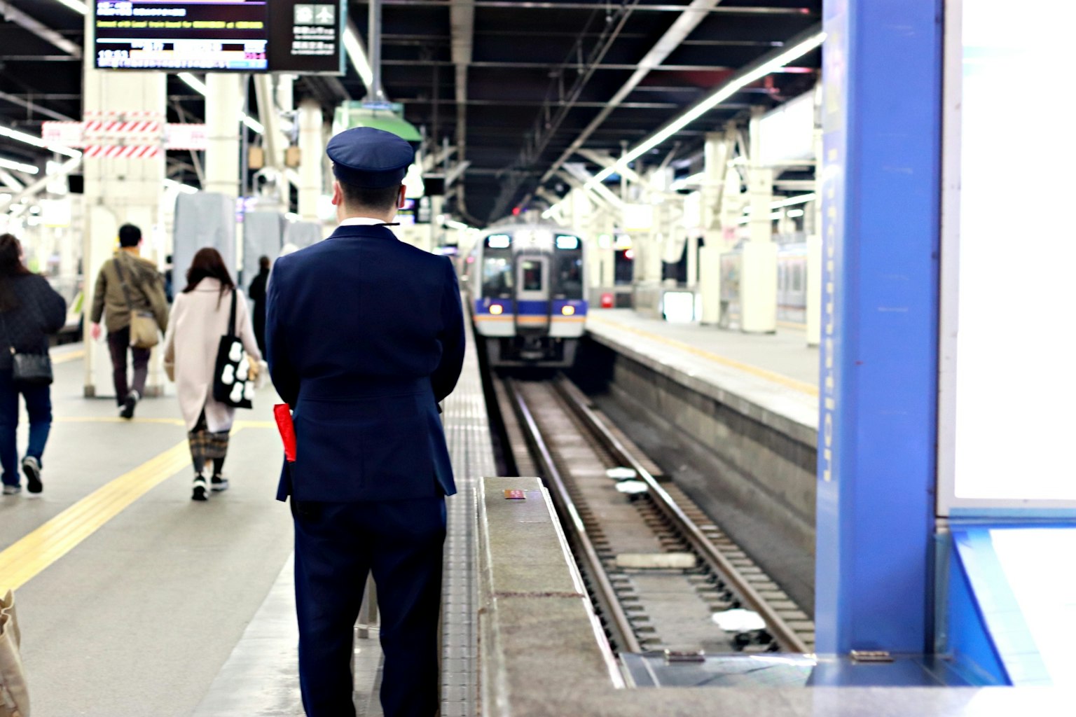 ตำรวจยืนอยู่ที่สถานีรถไฟพร้อมผู้โดยสารและรถไฟที่มาถึง