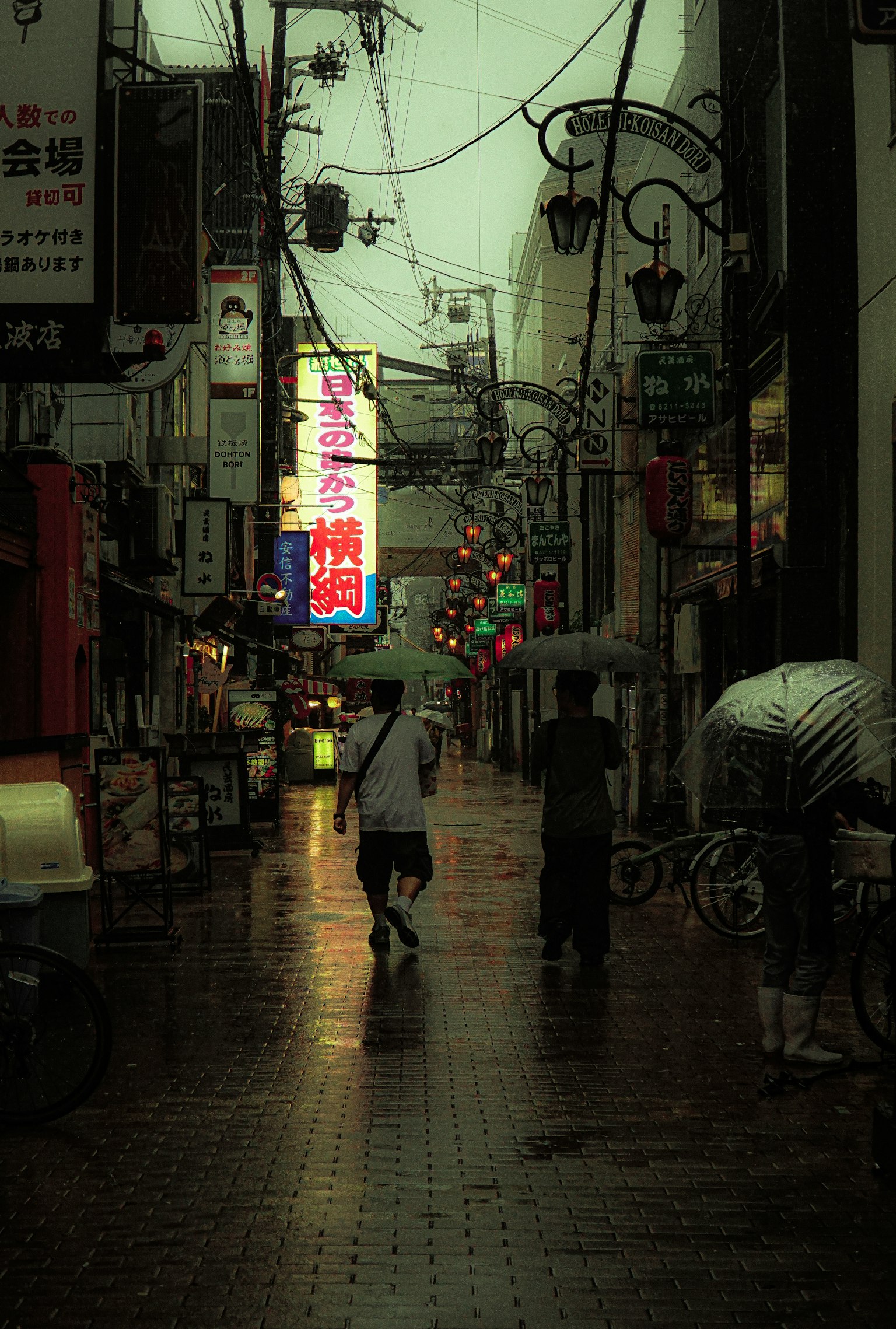 人在雨中的小巷里走，霓虹灯和倒影