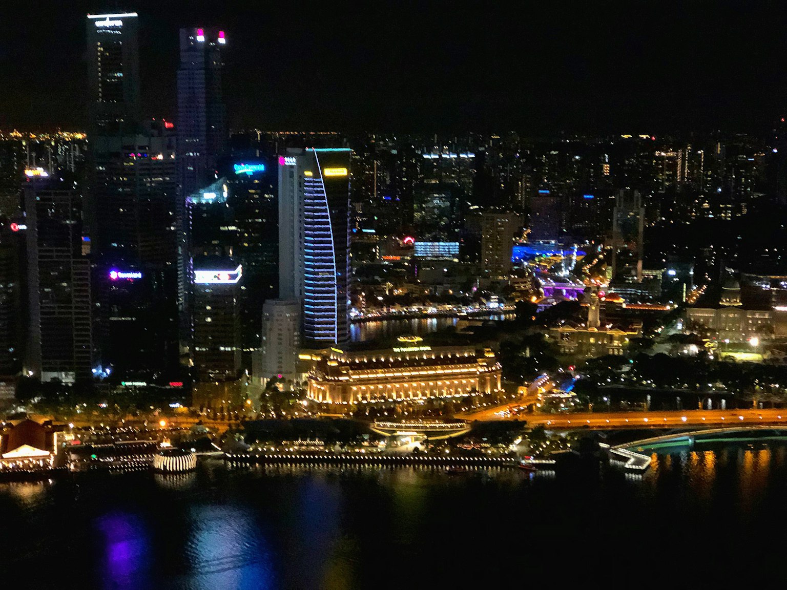 Pemandangan malam yang menakjubkan dari Singapura dengan gedung pencakar langit yang diterangi dan tepi laut