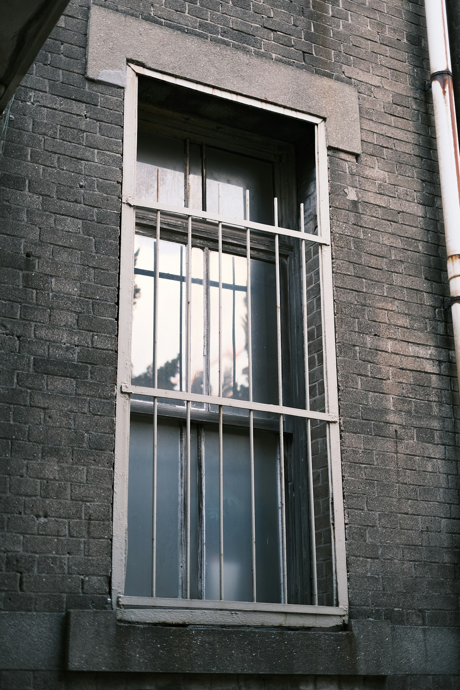 Window with white bars set in a gray brick wall
