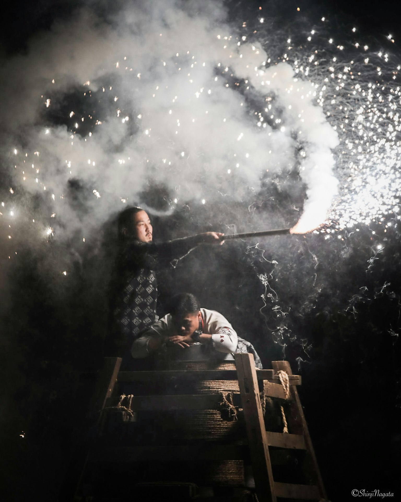 Person holding a firework against a smoky background at night