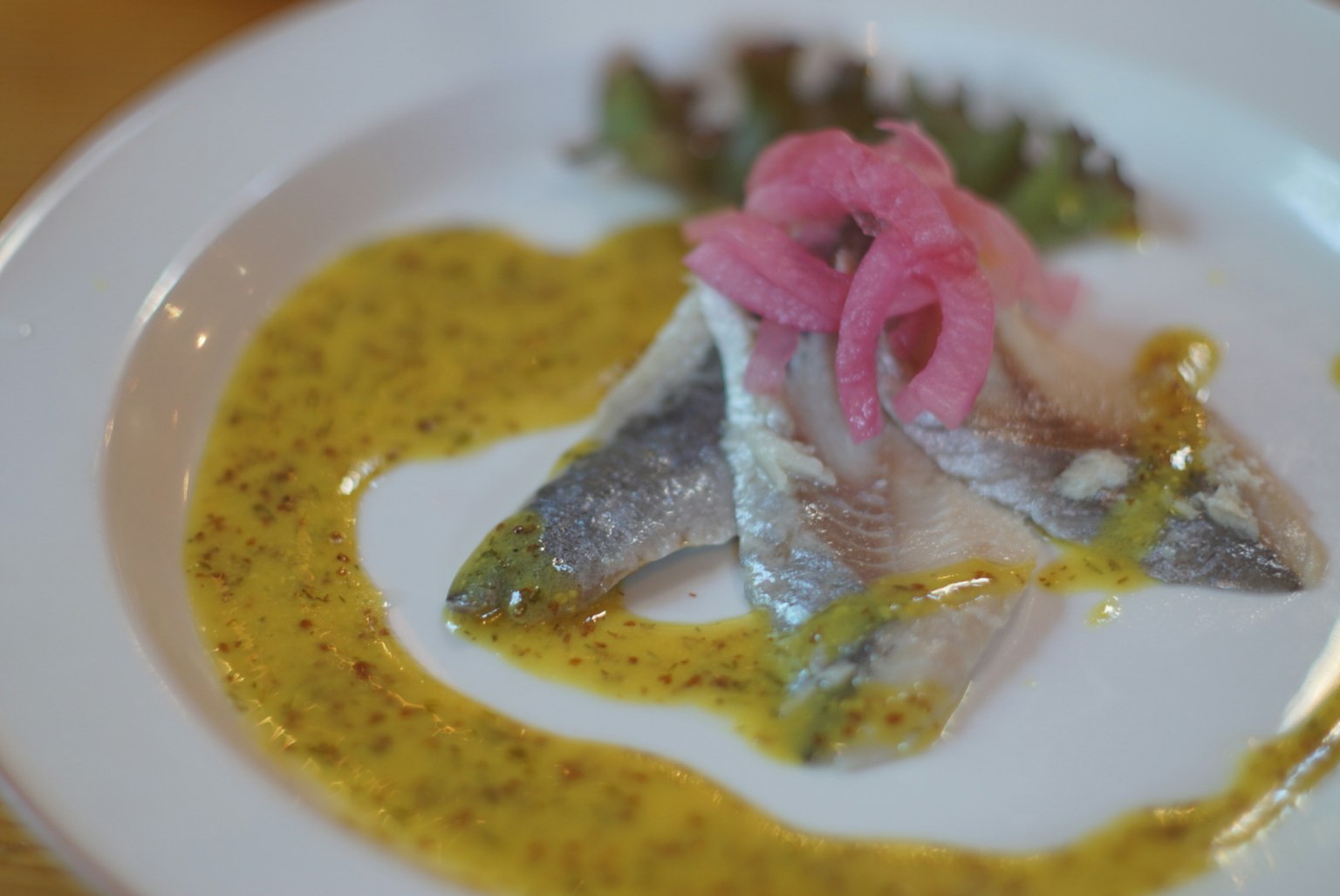 Pesce affettato guarnito con cipolle rosa e salsa