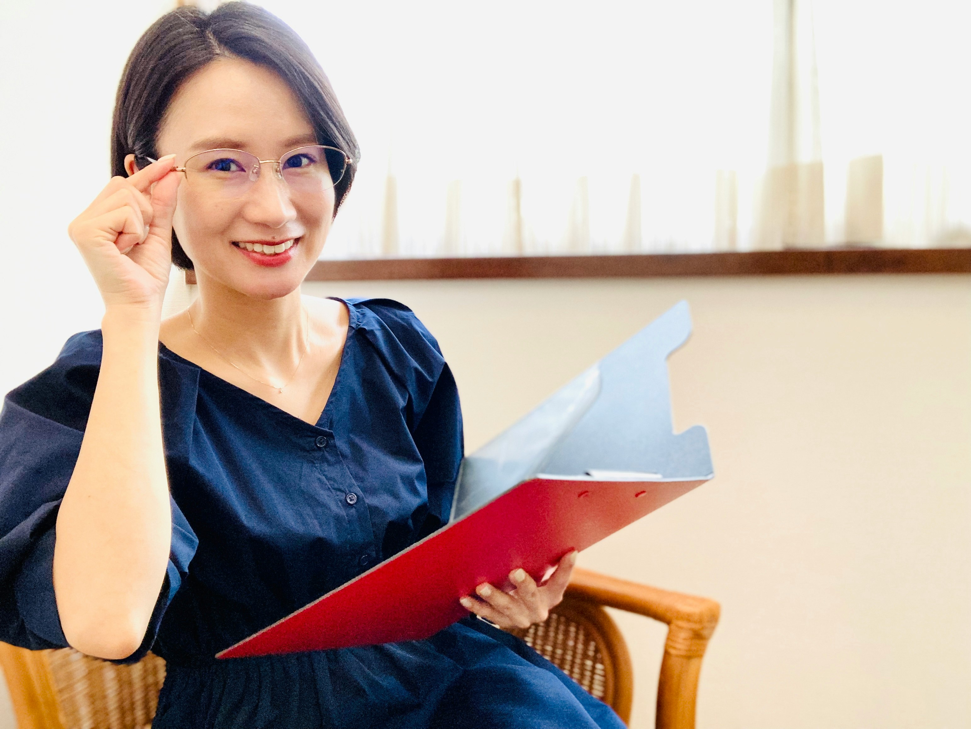 微笑的女性手持文件并触碰耳朵的办公场景
