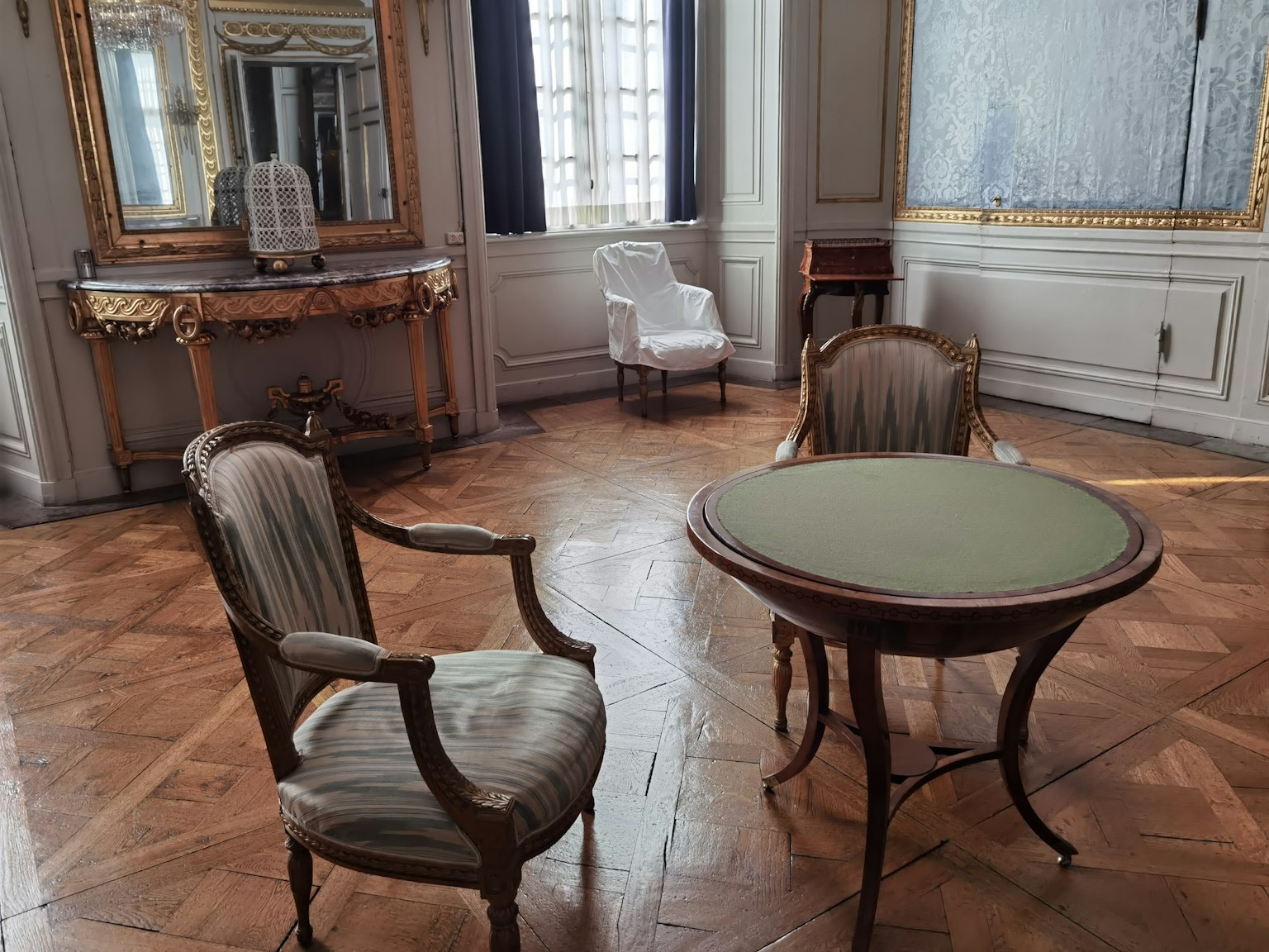 Chaises et table classiques disposées dans une pièce élégante avec lumière naturelle et un grand miroir