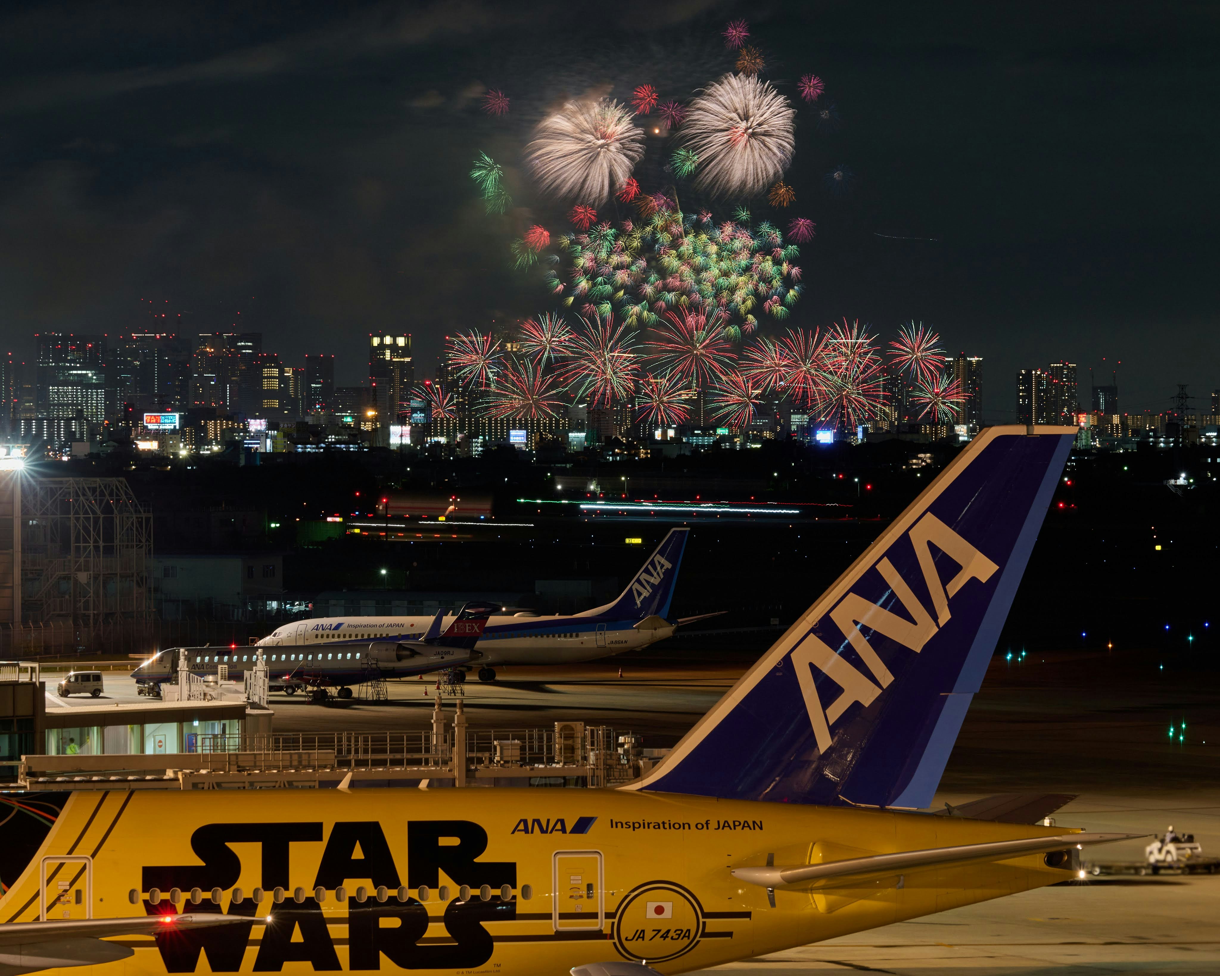 夜の空港でANA機体と打ち上げ花火が見える夜景
