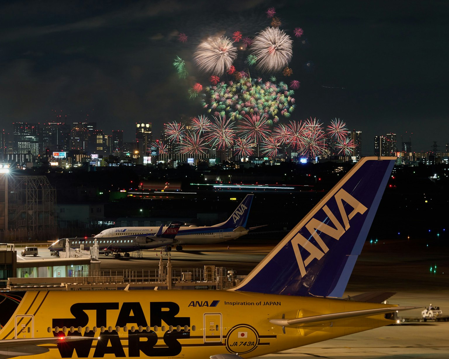 Avion ANA avec des feux d'artifice dans le ciel nocturne