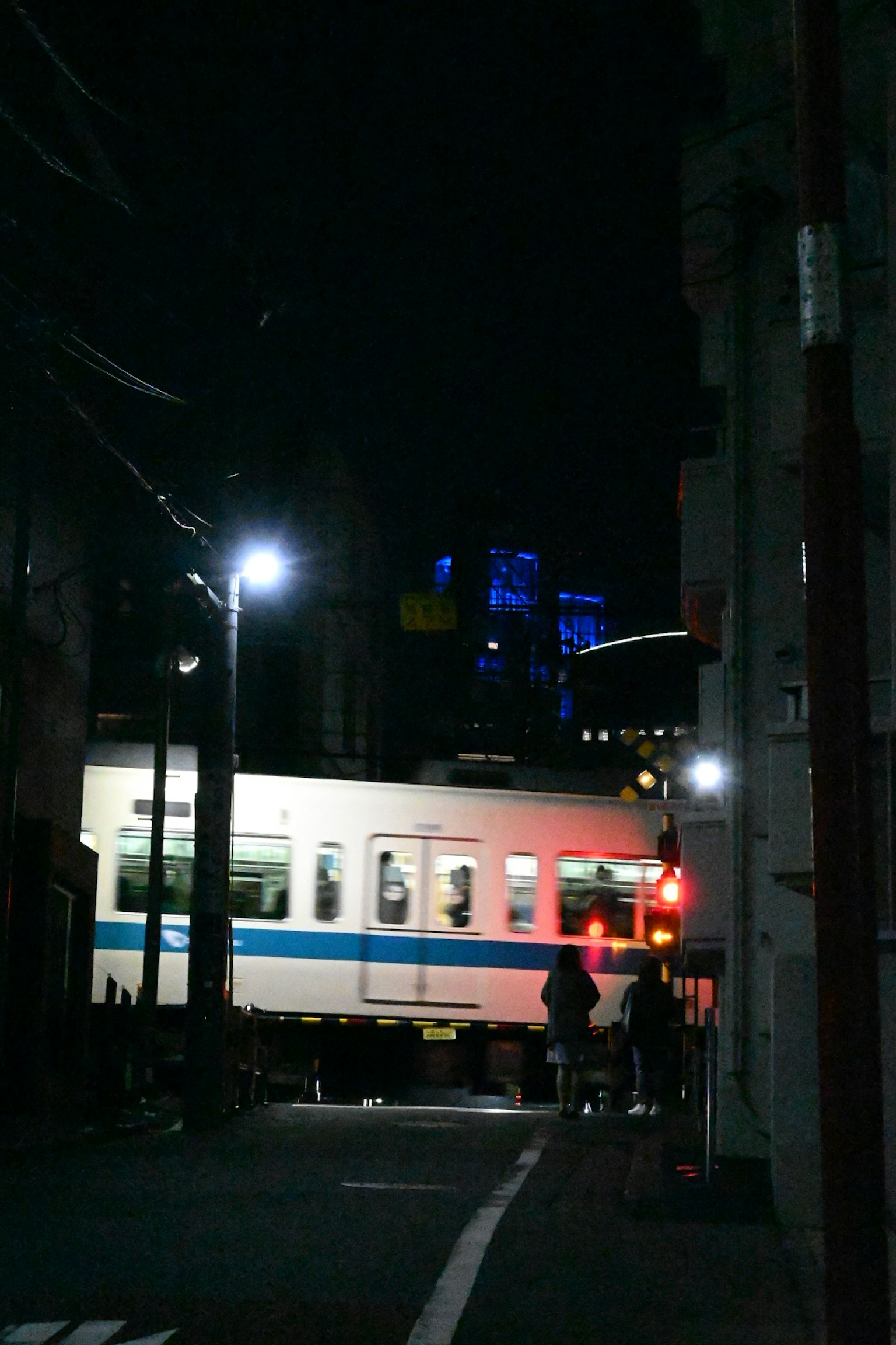 Tren pasando por una calle oscura con luces de la ciudad