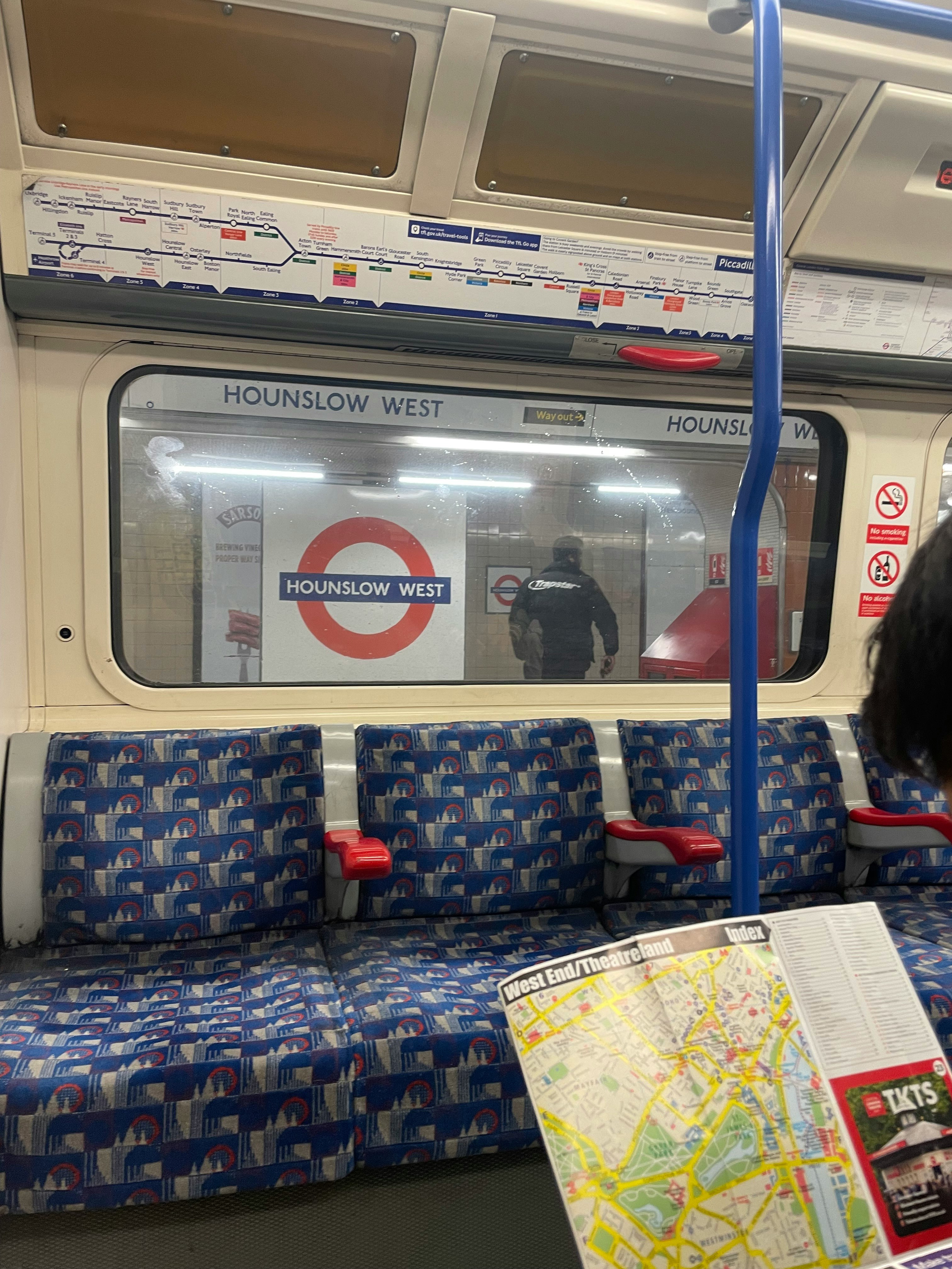 ロンドンの地下鉄車内で座席と吊り広告が見える車窓