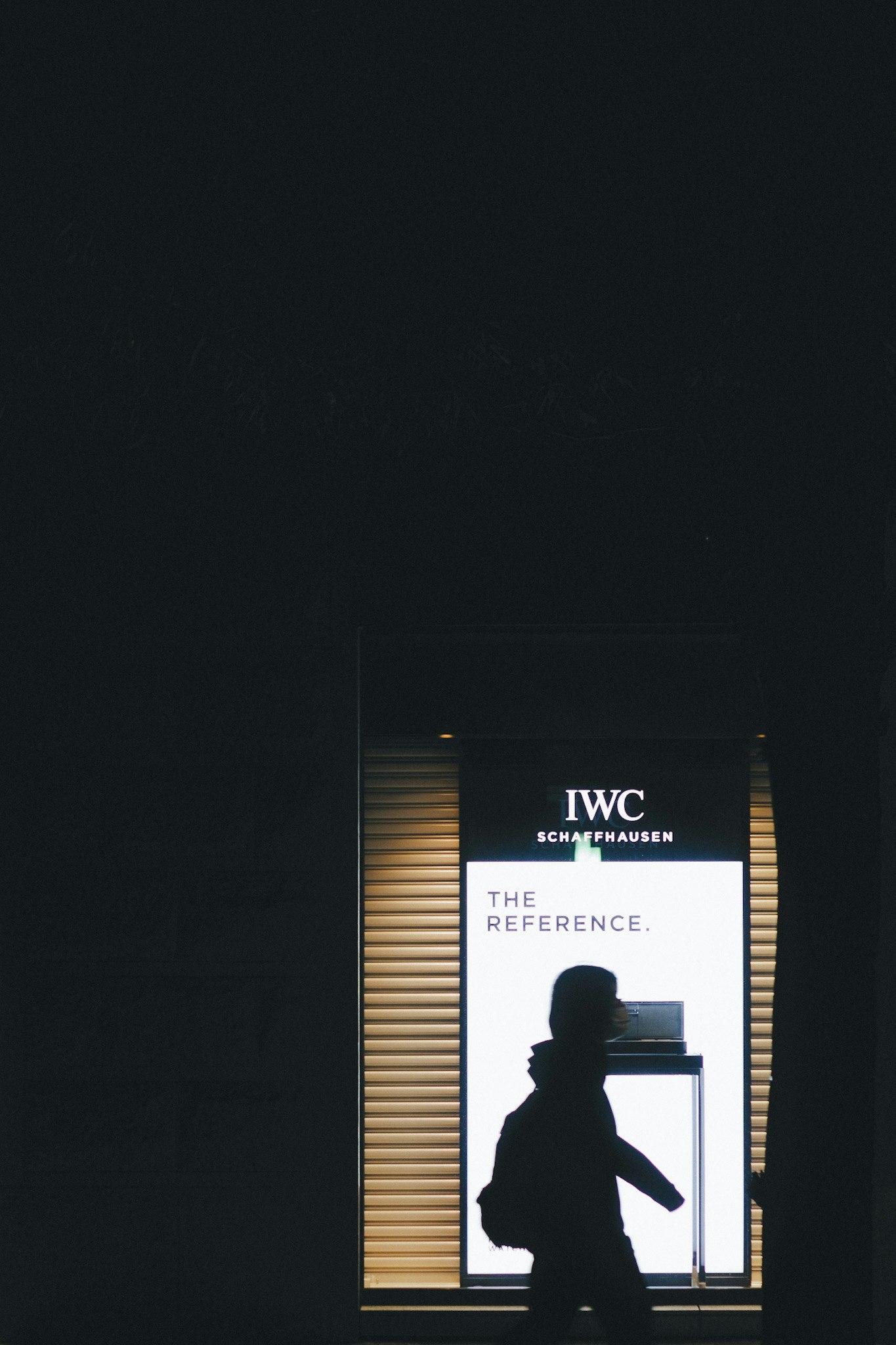 entrada nocturna con letrero de IWC y una silueta