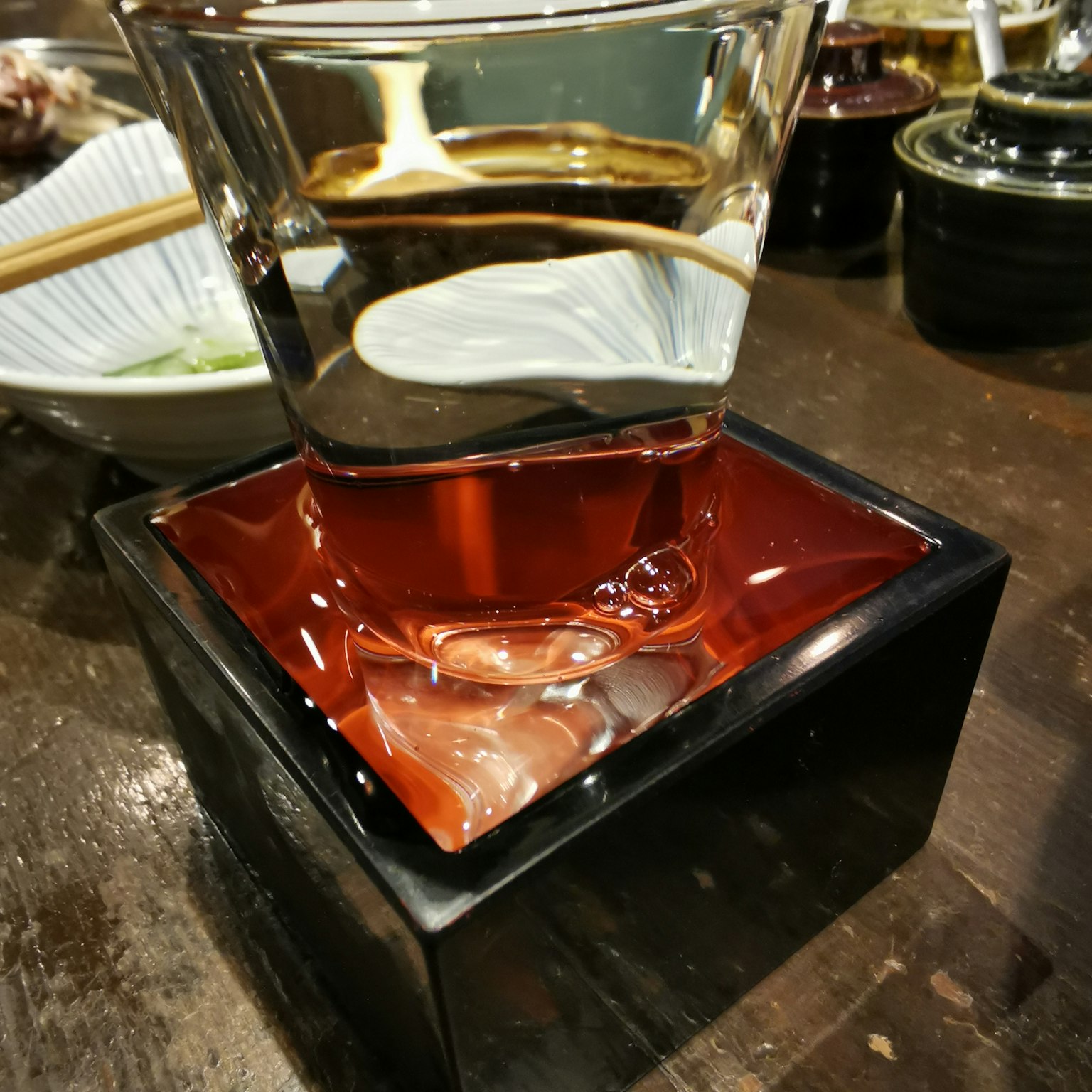 一個透明液體的玻璃杯放在一個黑色方形容器上