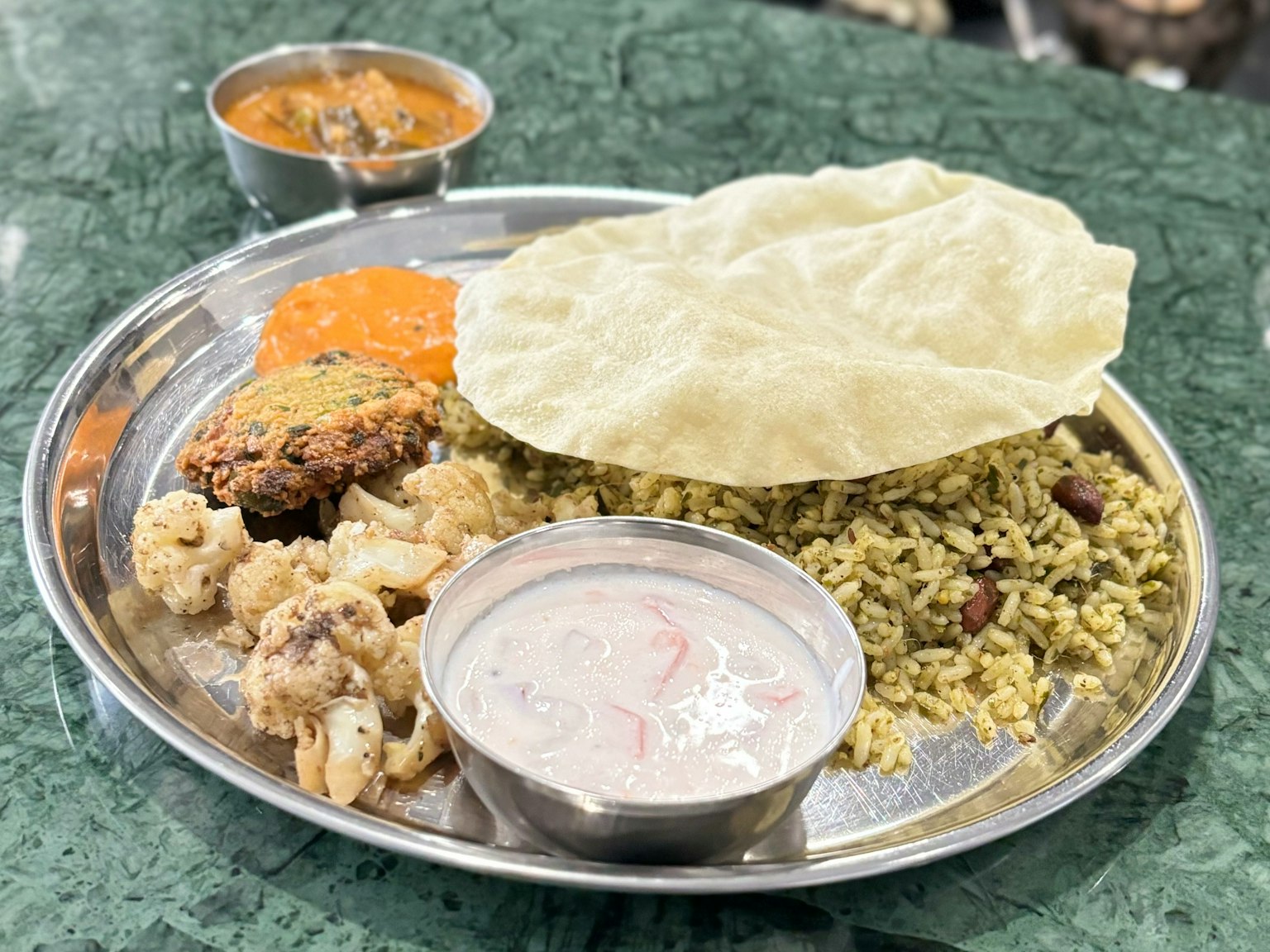 Piring masakan India dengan kari, nasi, papad, yogurt, dan sayuran sabzi