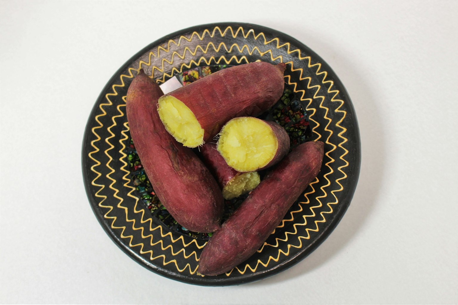 Patate dolci disposte su un piatto nero decorato