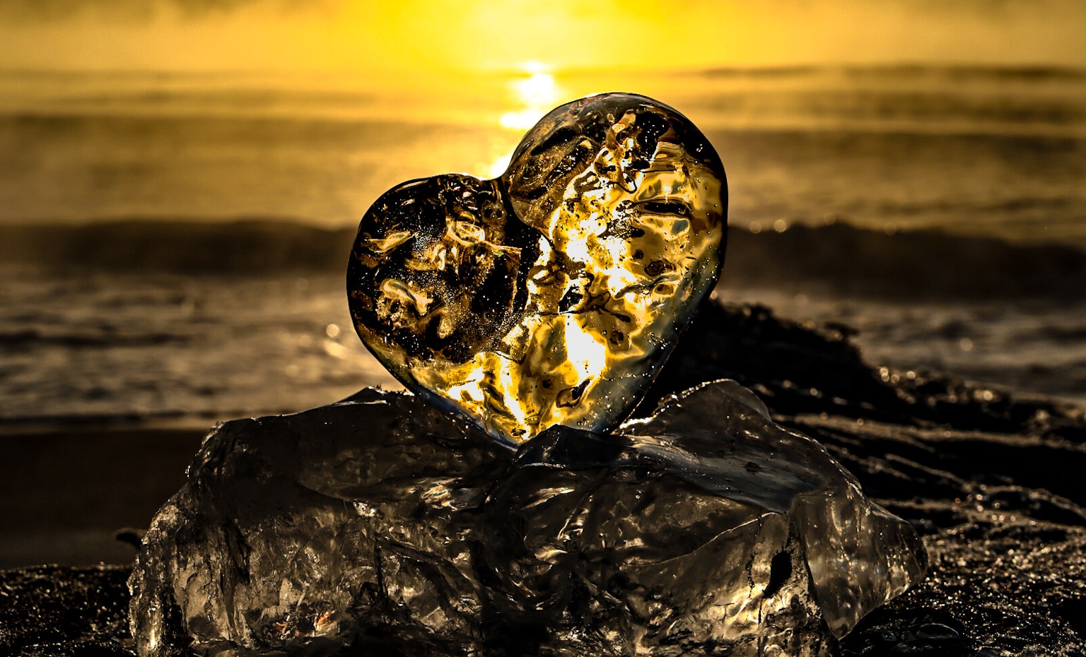 Roca en forma de corazón en la playa con luz solar brillando a través