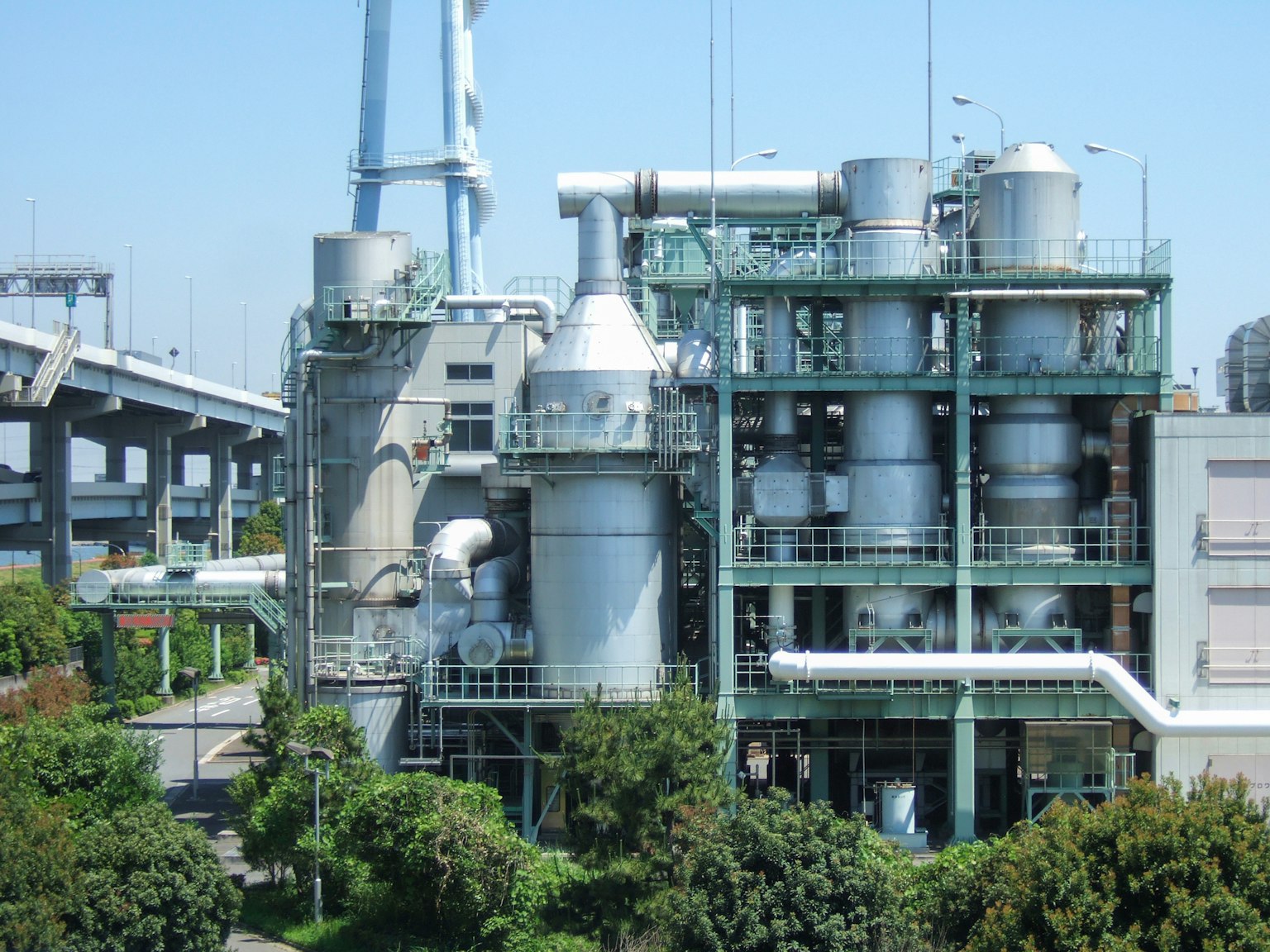 Exterior of an industrial facility featuring green structures and metal tanks