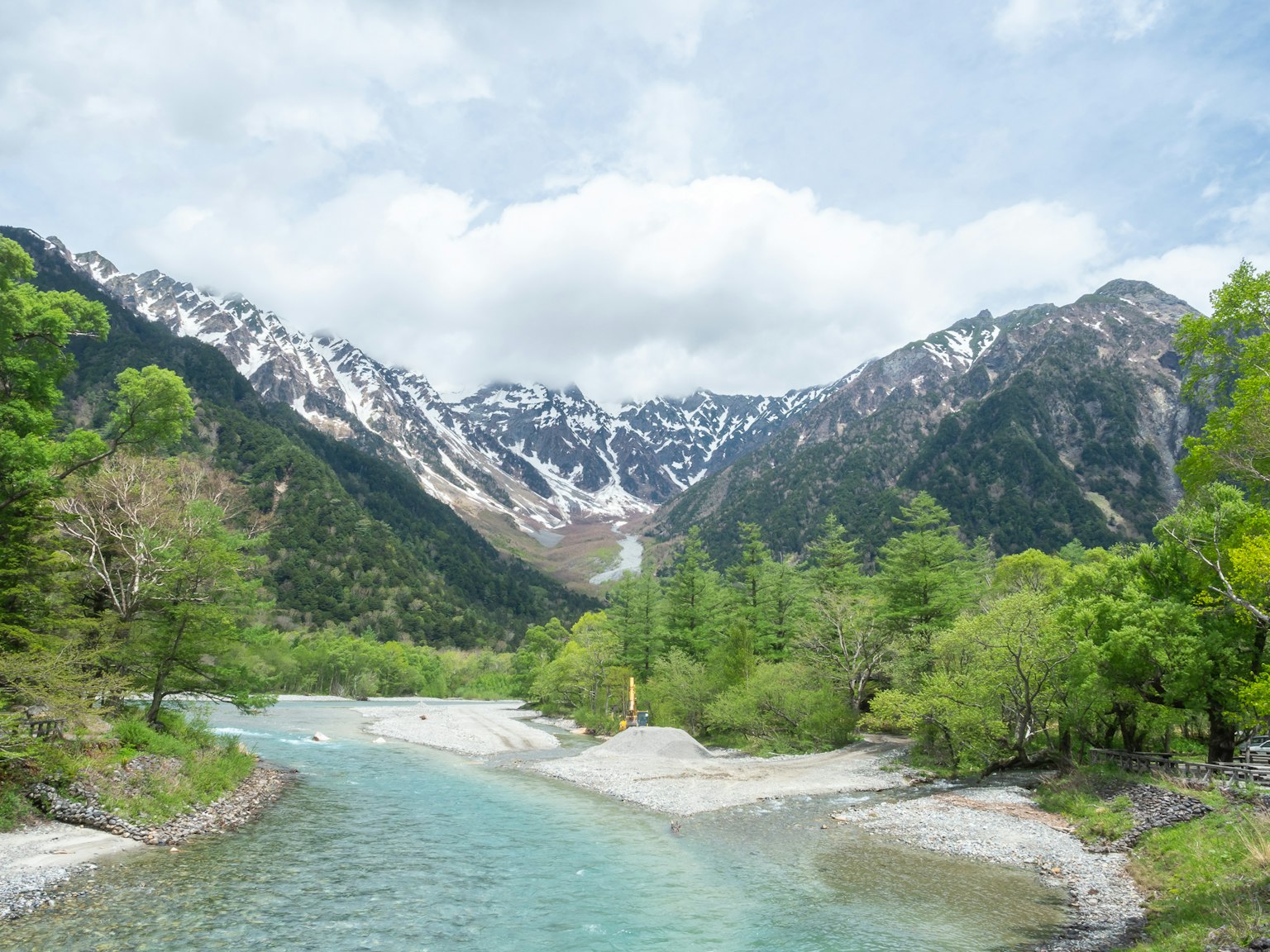 雪山與郁郁蔥蔥的綠色之間流淌的清澈河流的風景
