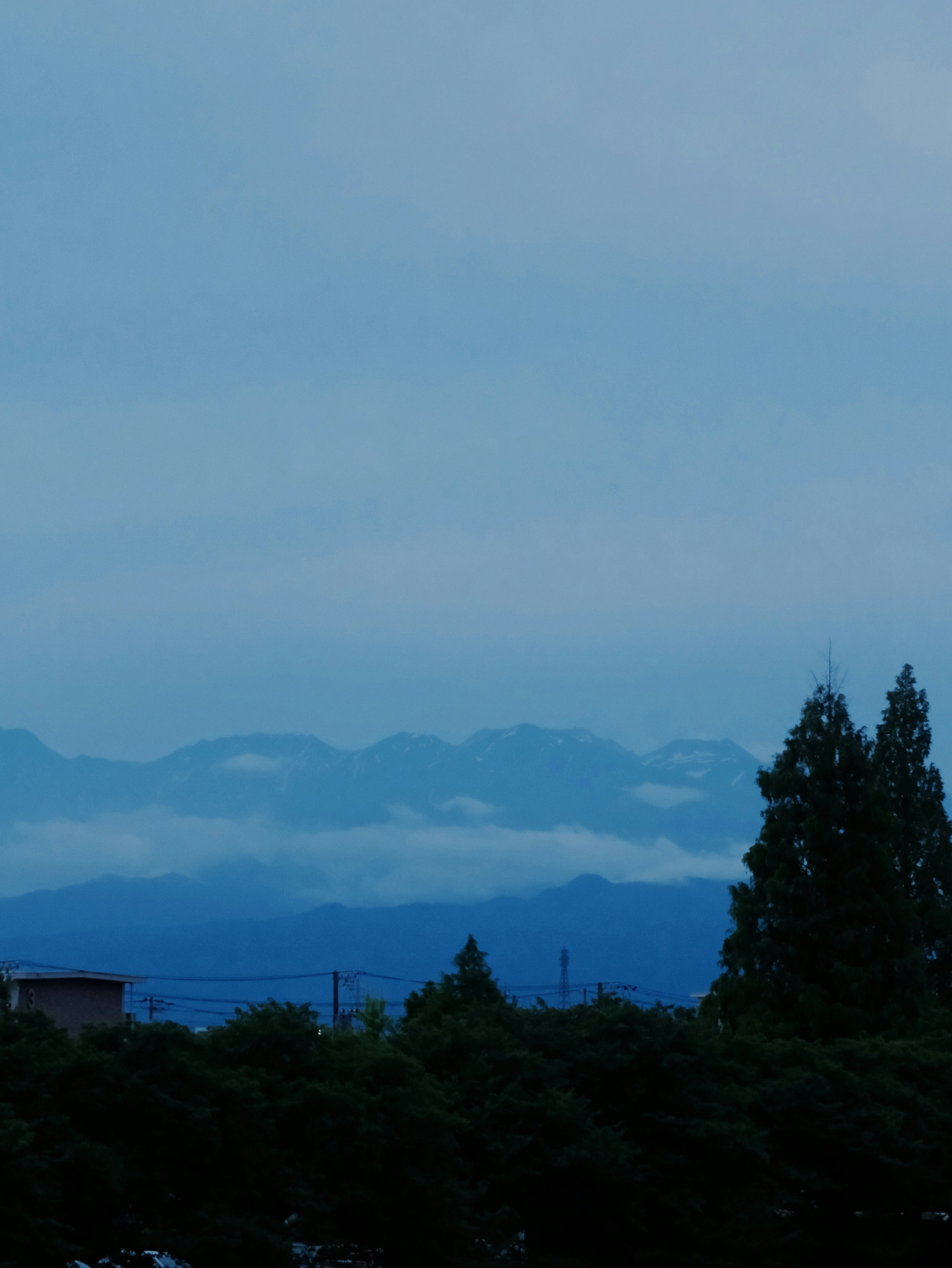 富山の山並みを望む夕暮れの空と森のシルエット