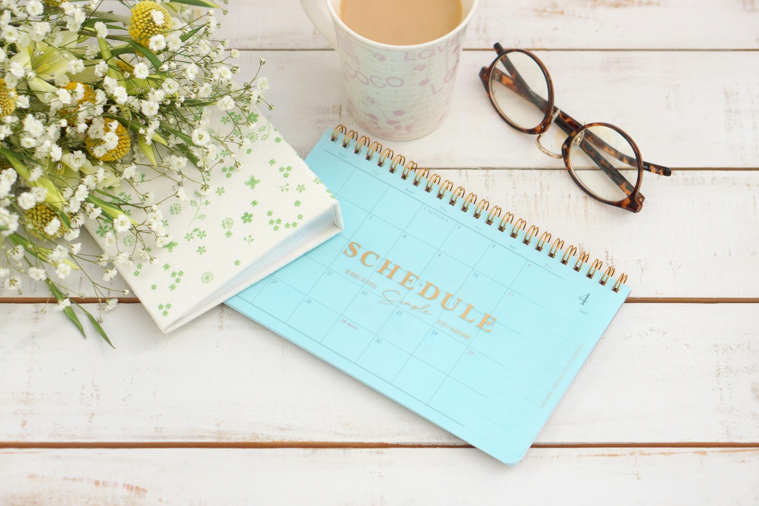 Una scena da scrivania con un calendario blu e un mazzo di fiori