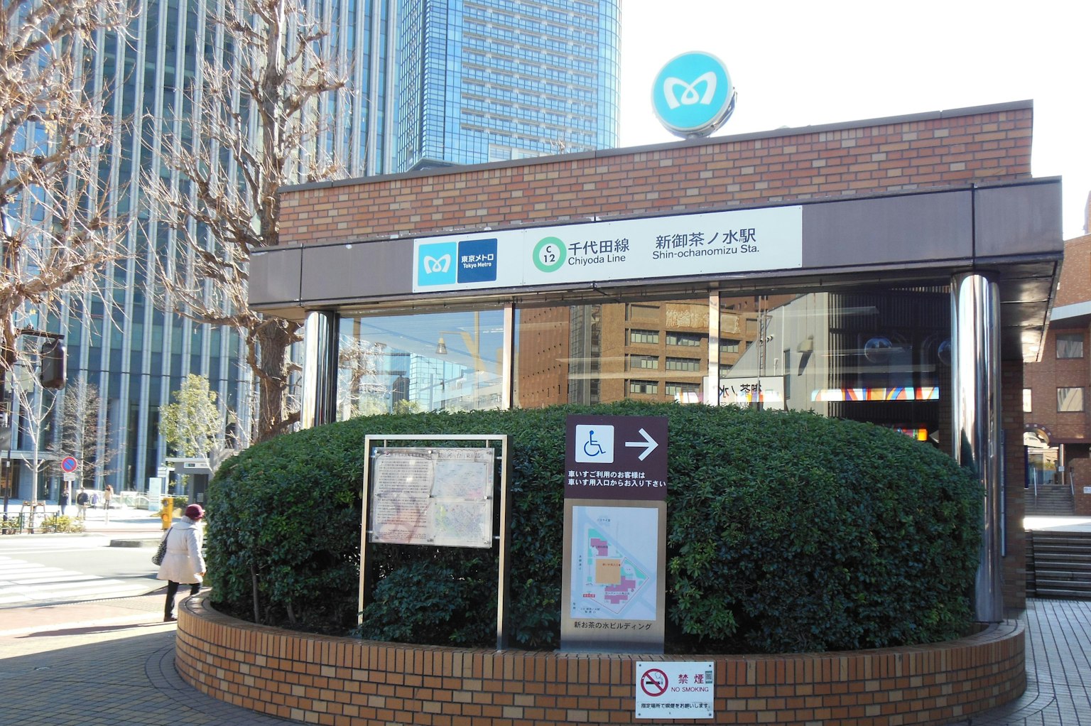 Entrée d'une station entourée de verdure avec des panneaux colorés et des tableaux d'information