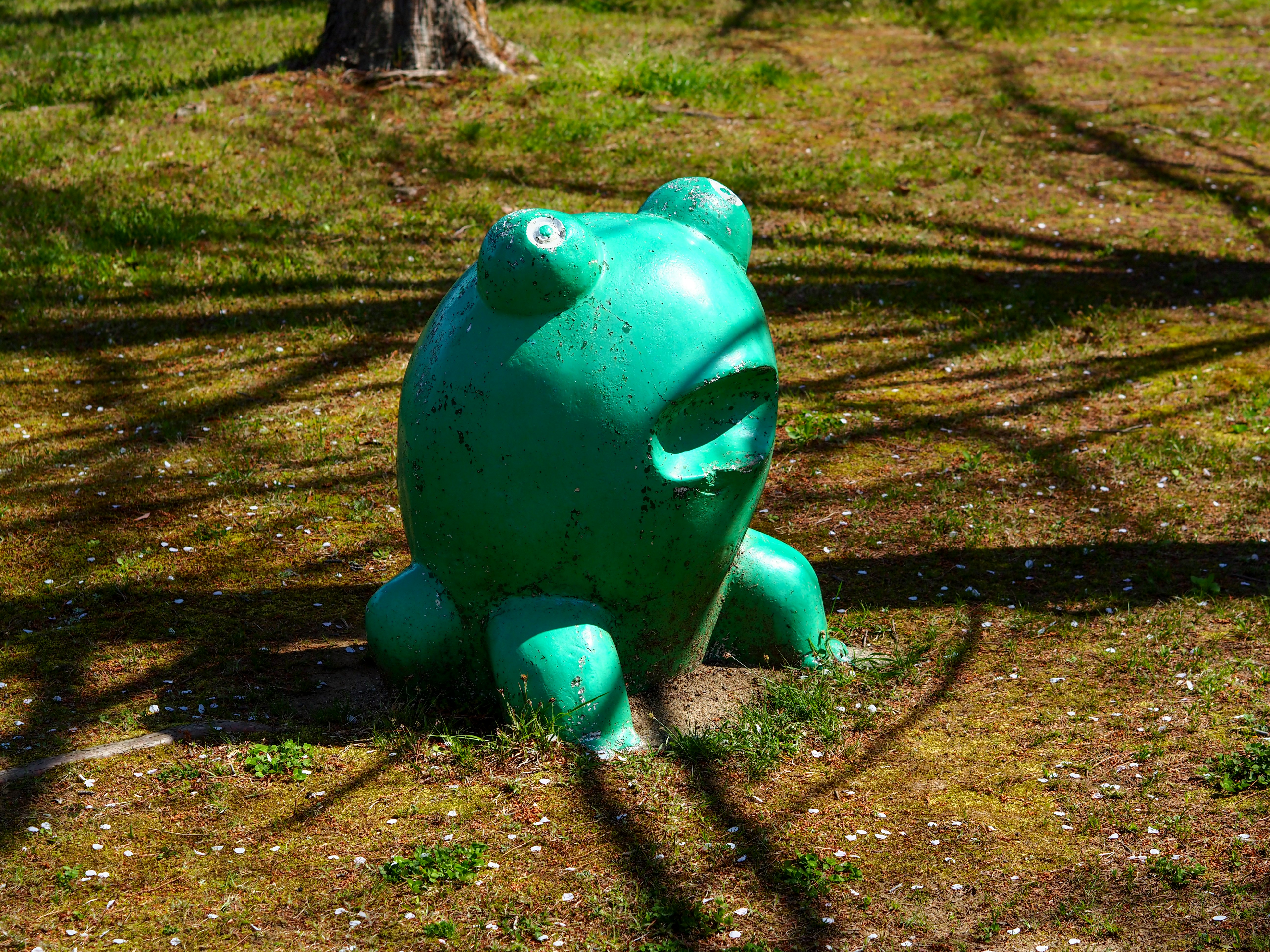 estatua de rana verde sentada sobre el césped