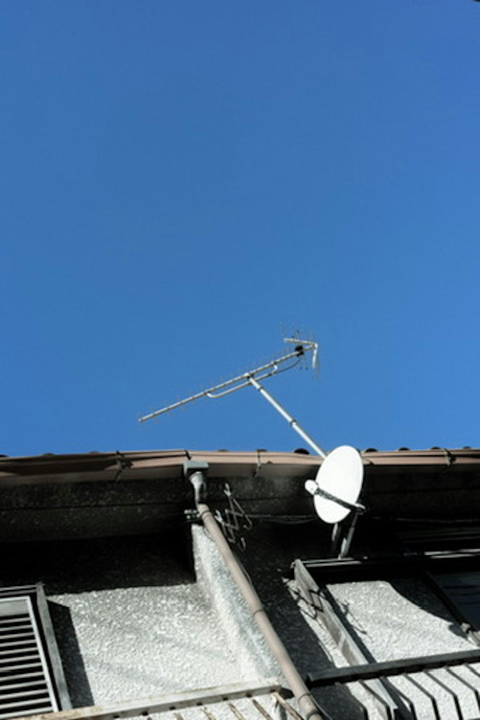 Antenna e sistema satellitare su un tetto sotto un cielo azzurro