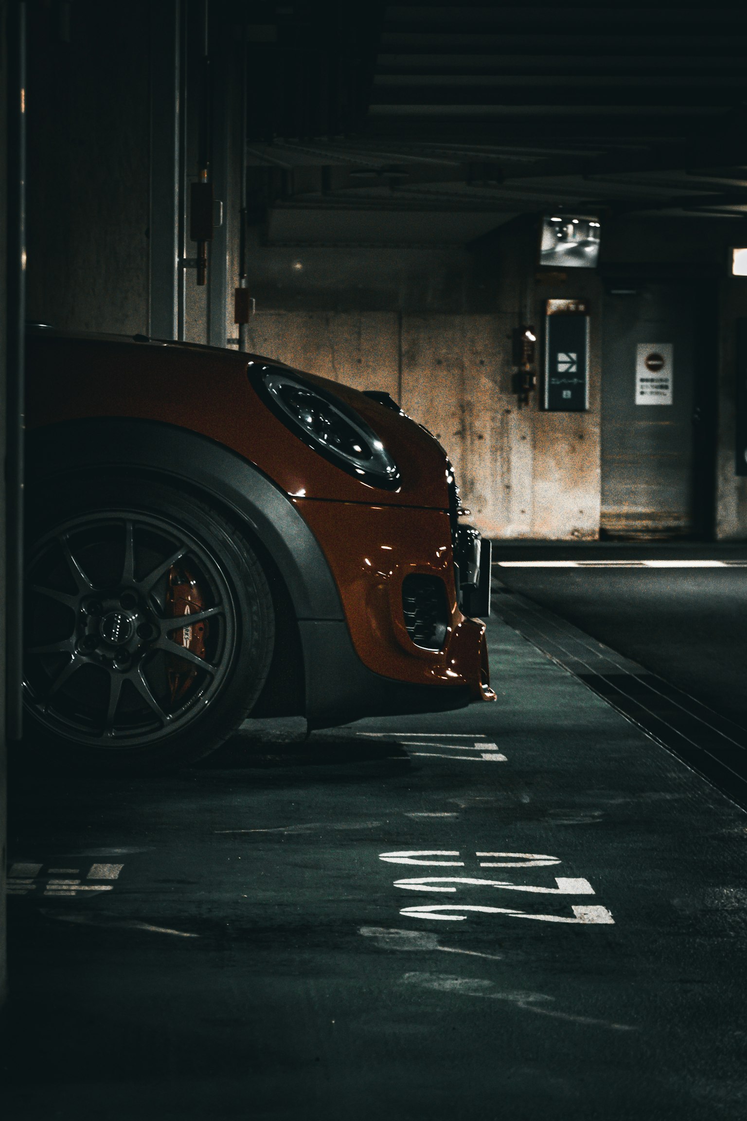 Vue latérale d'une voiture de sport rouge garée dans un garage faiblement éclairé