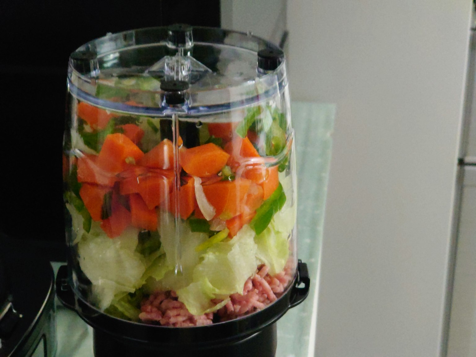 Conteneur transparent de robot culinaire rempli de légumes hachés et de viande