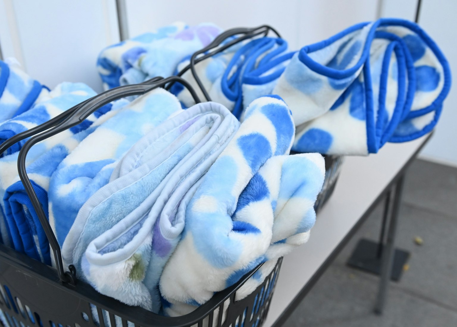 A basket filled with blue blankets on a table