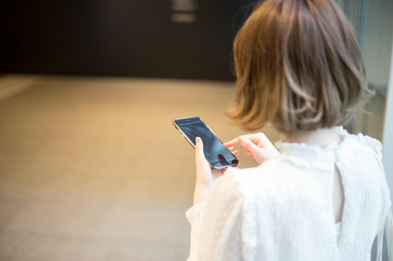 Woman using smartphone from behind Simple background
