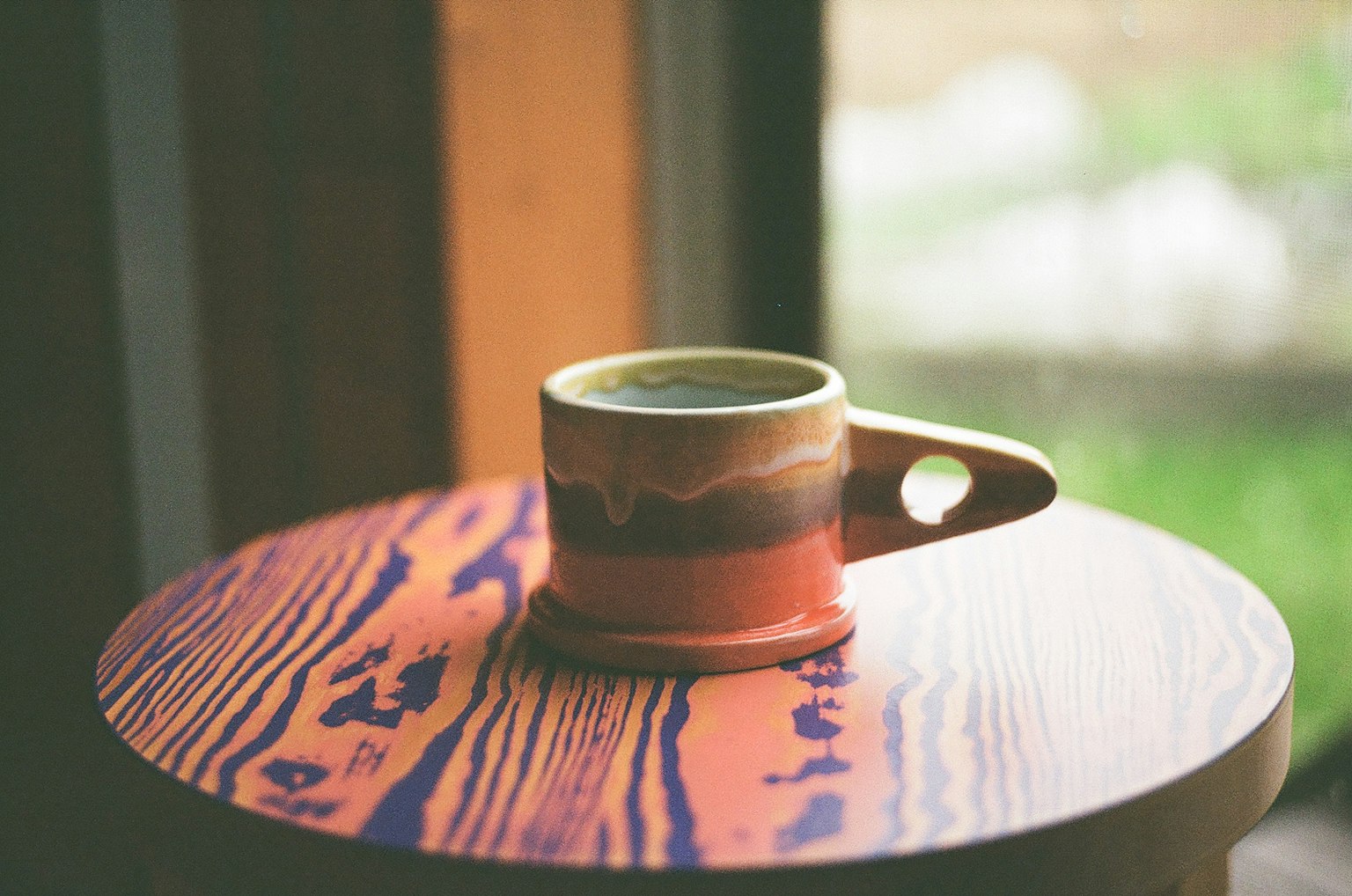 Taza de cerámica colorida colocada sobre una mesa de madera