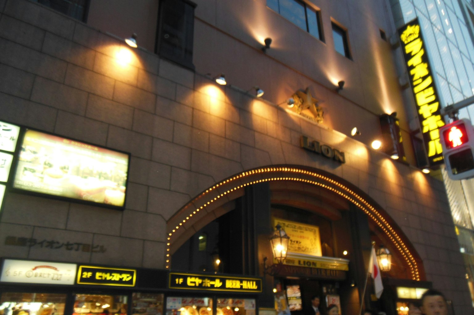 Restaurant exterior in a city at night featuring bright signage and an arched entrance
