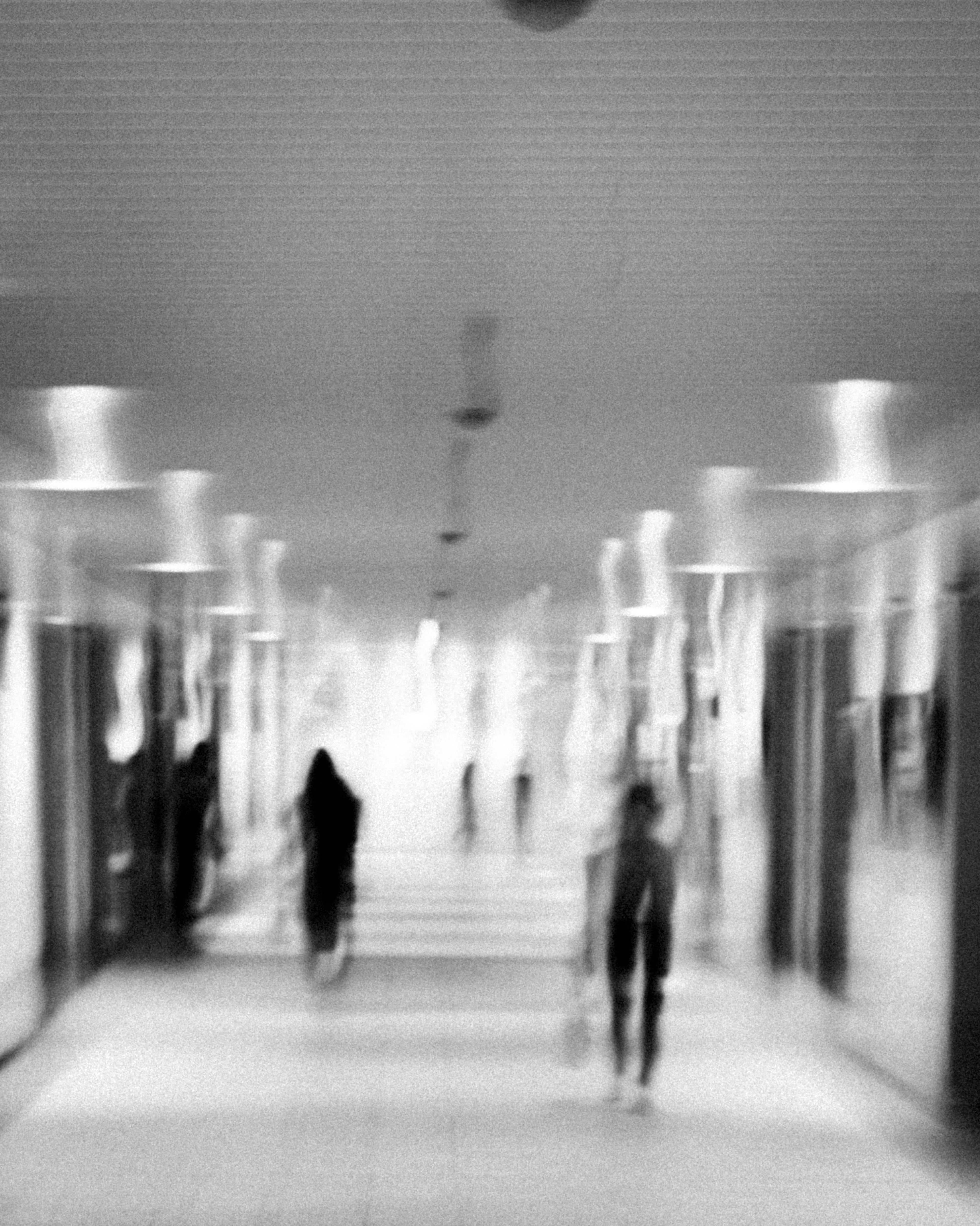 blurred figures walking through an arched corridor