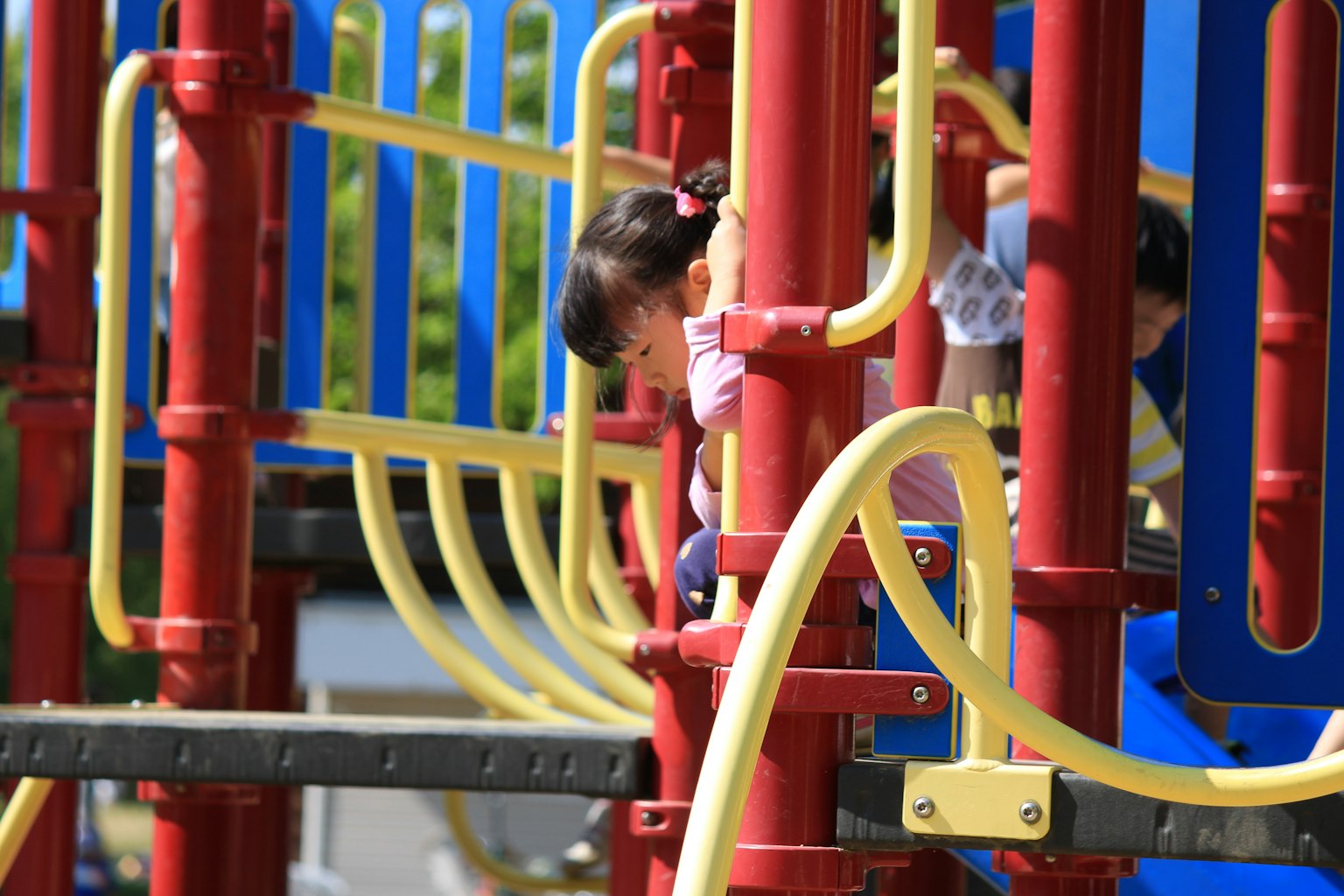 孩子們在五彩的遊樂場結構上玩耍，包含紅色和黃色元素