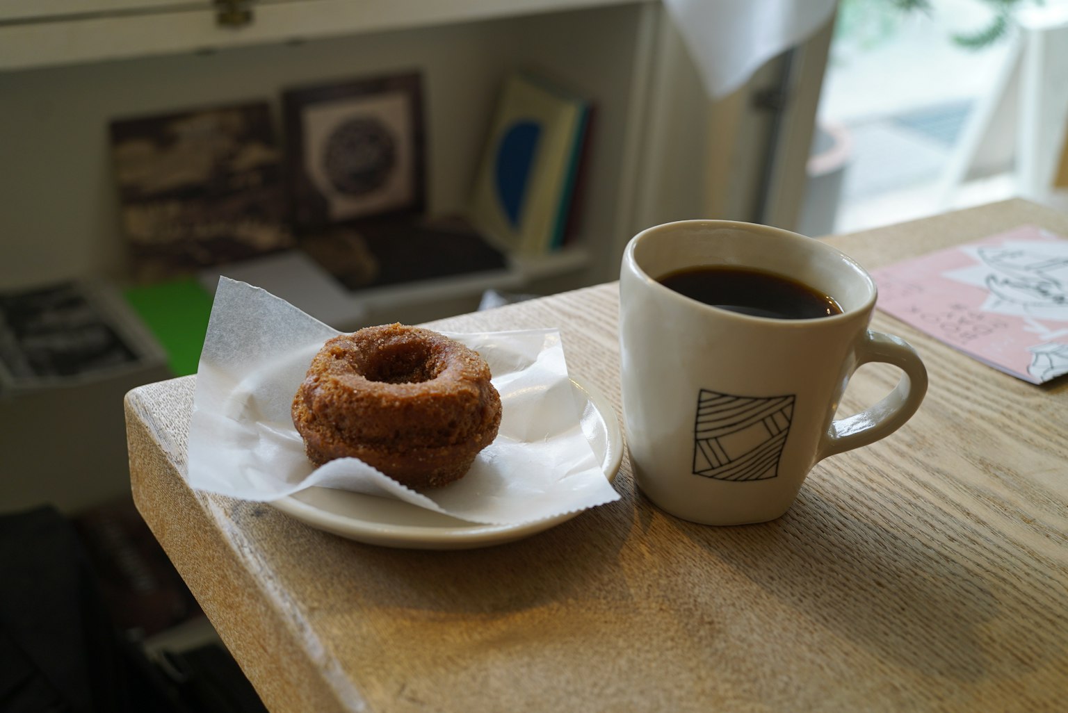 Secangkir kopi dan donat di atas piring di meja kafe