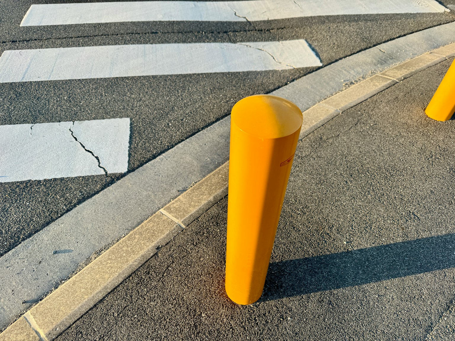 Un bollard jaune près d'un passage piéton sur le pavé