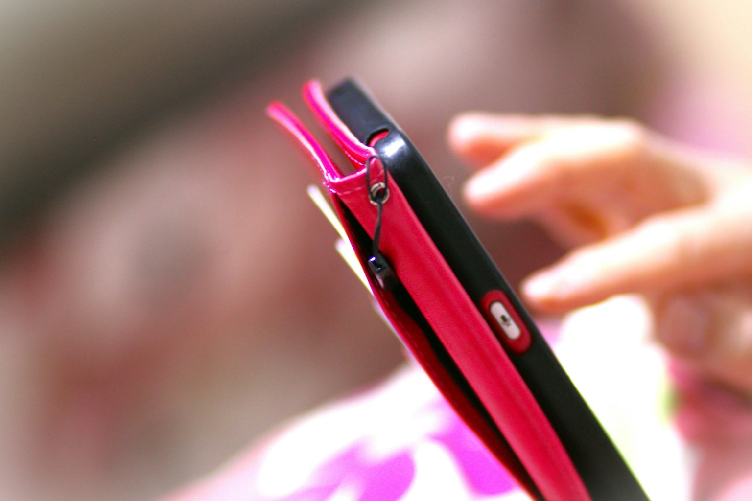 Close-up of a smartphone with a pink case being held