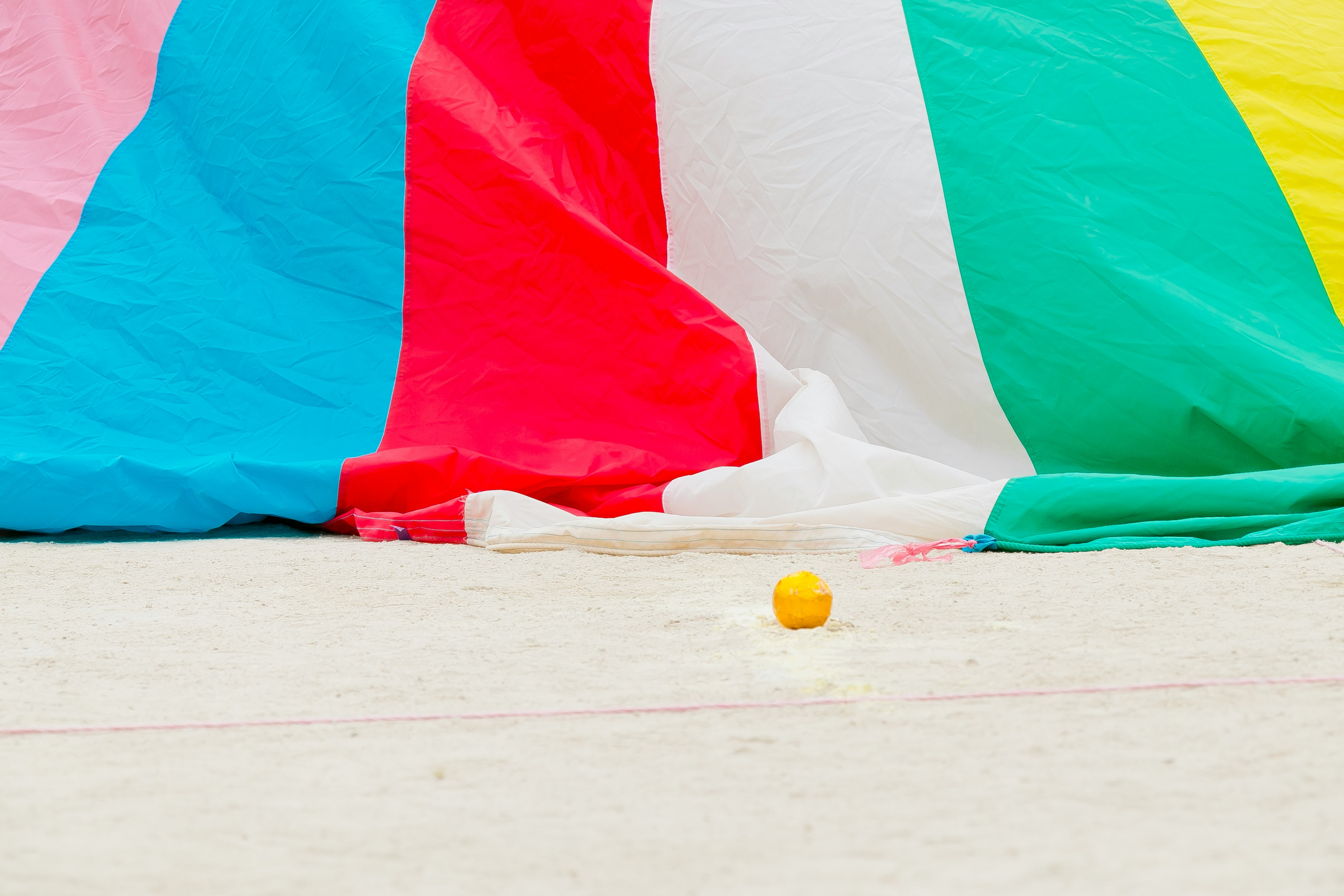 colorful parachute spread on sandy beach