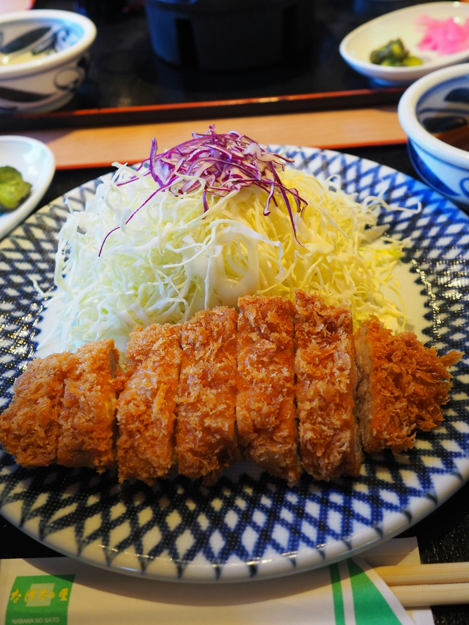 Cotoletta di maiale impanata affettata servita su un piatto con cavolo tritato