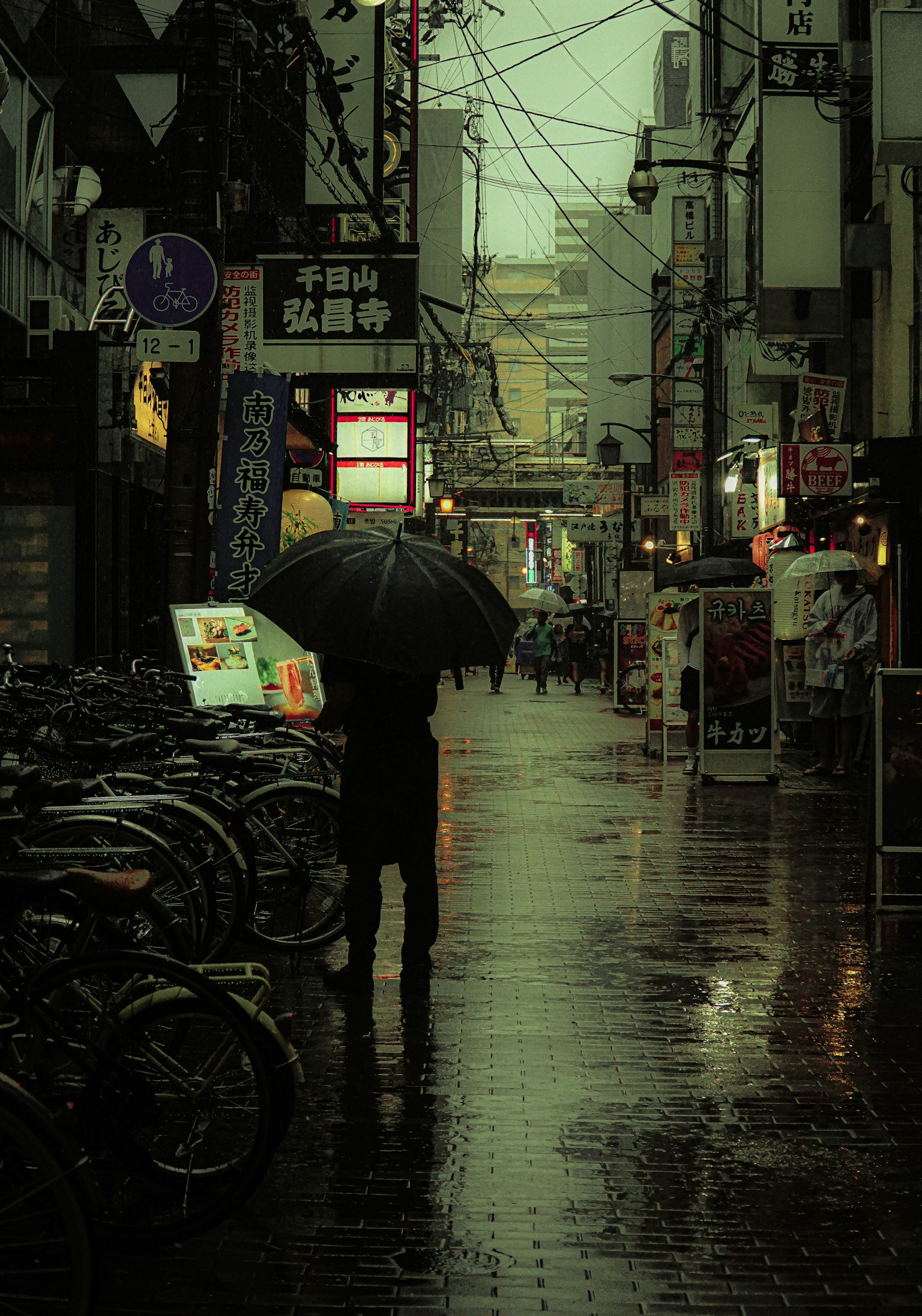一个人在雨中撑着伞走在城市街道上