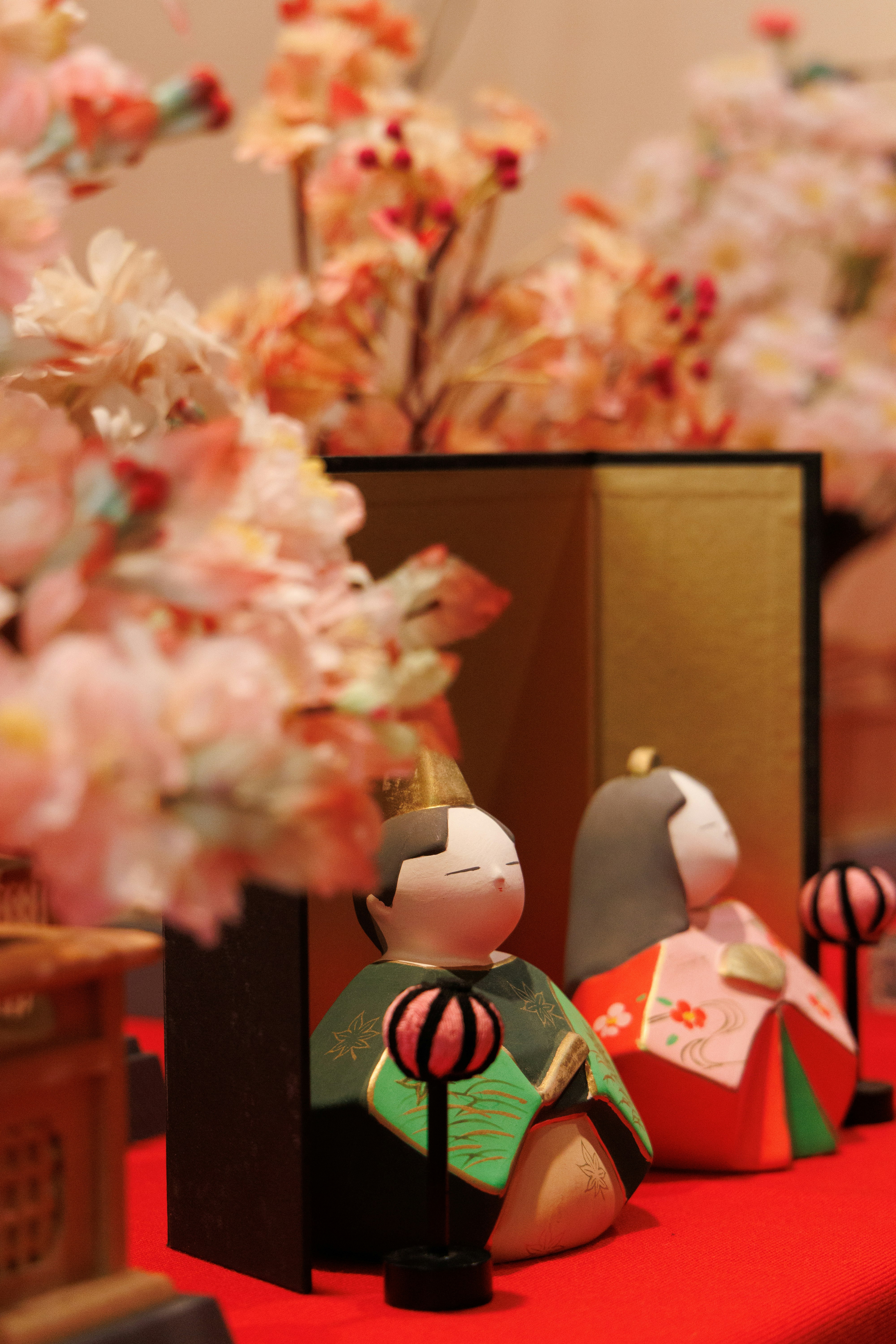 赤い台座の和風人形と桜の花飾りのある室内