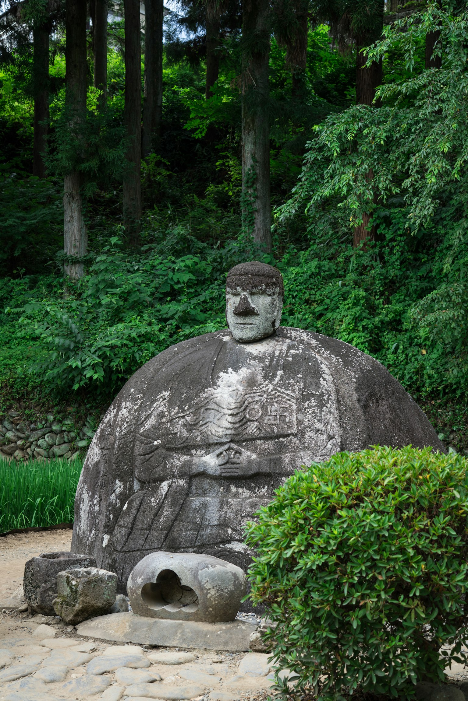 Stone statue of a Buddha surrounded by greenery