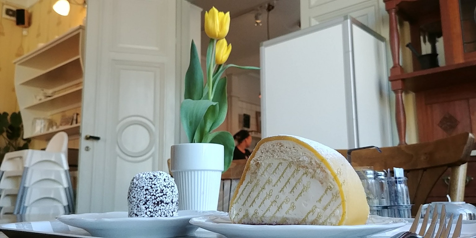 Ein Teller mit Käse und Dessert auf einem Tisch mit einer Vase Tulpen