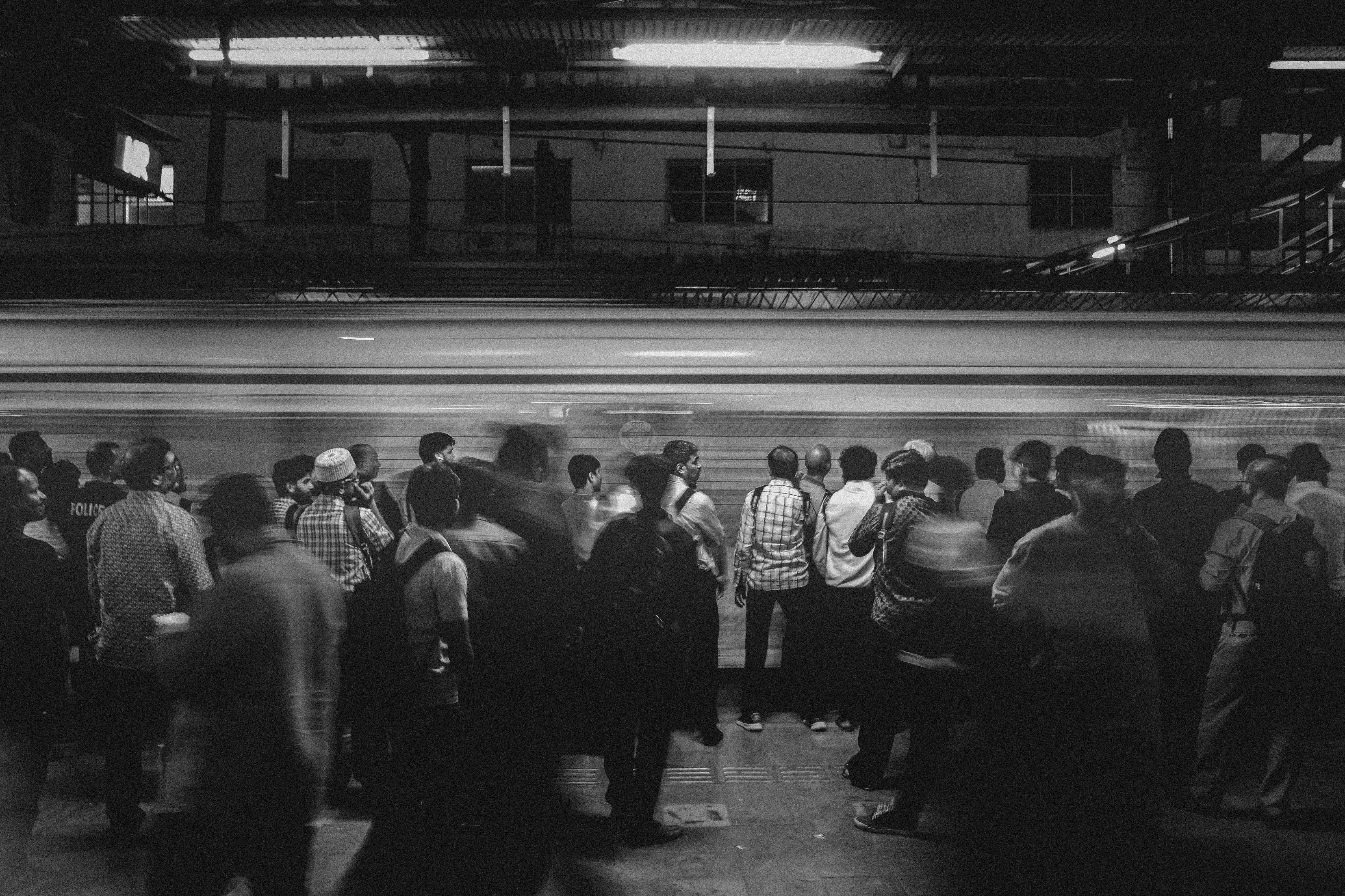 駅のホームで列に並ぶ人々のシルエット