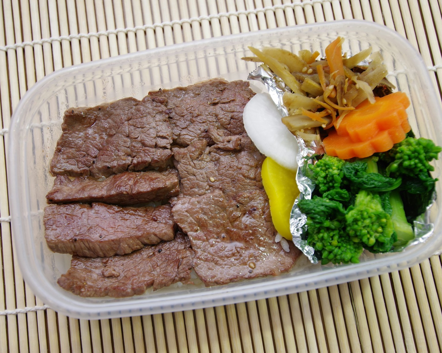 Daging sapi iris disajikan dalam kotak bento dengan sayuran