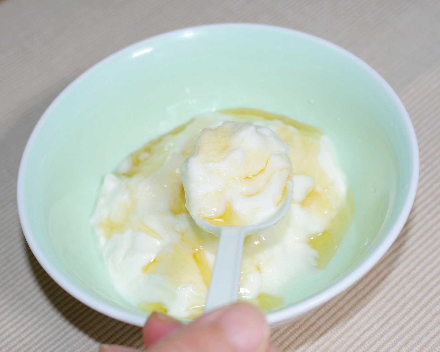Yogurt mescolato con miele in una ciotola verde chiaro