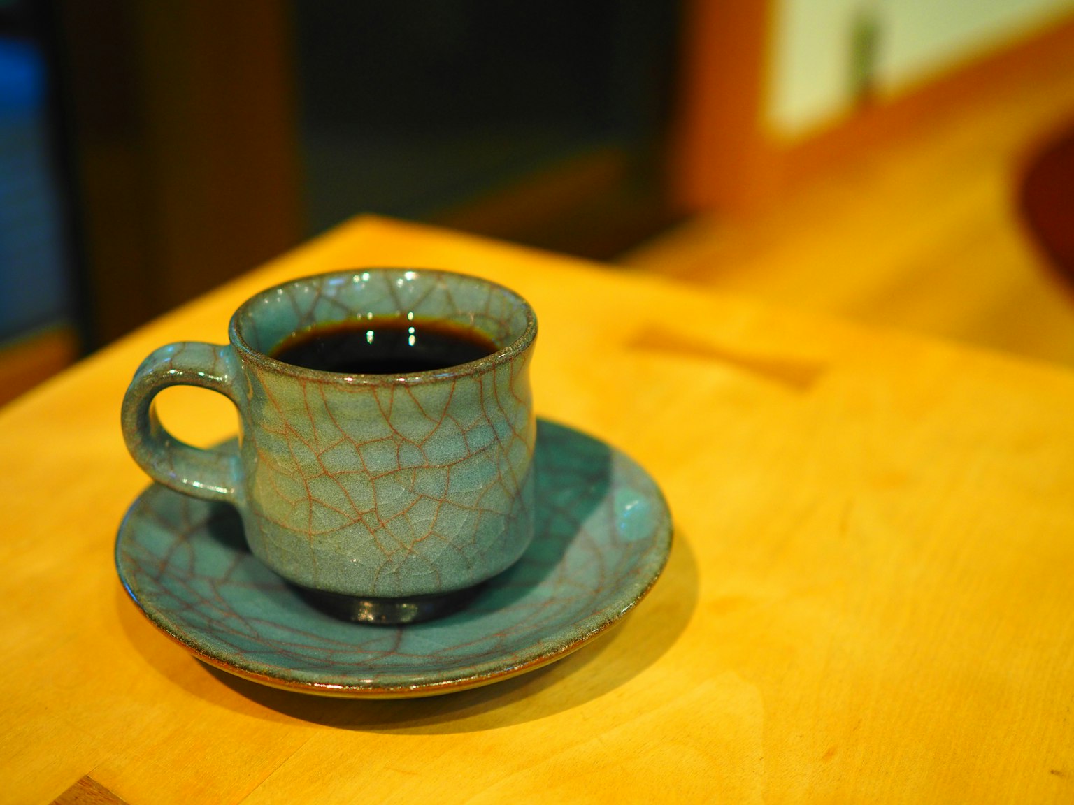 ถ้วยกาแฟเซรามิกสีน้ำเงินและจานวางอยู่บนโต๊ะไม้