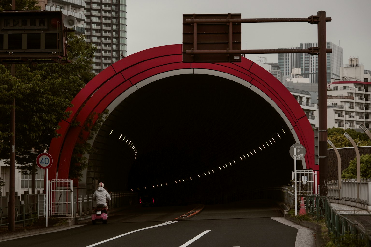 Red arch-shaped tunnel entrance with road view