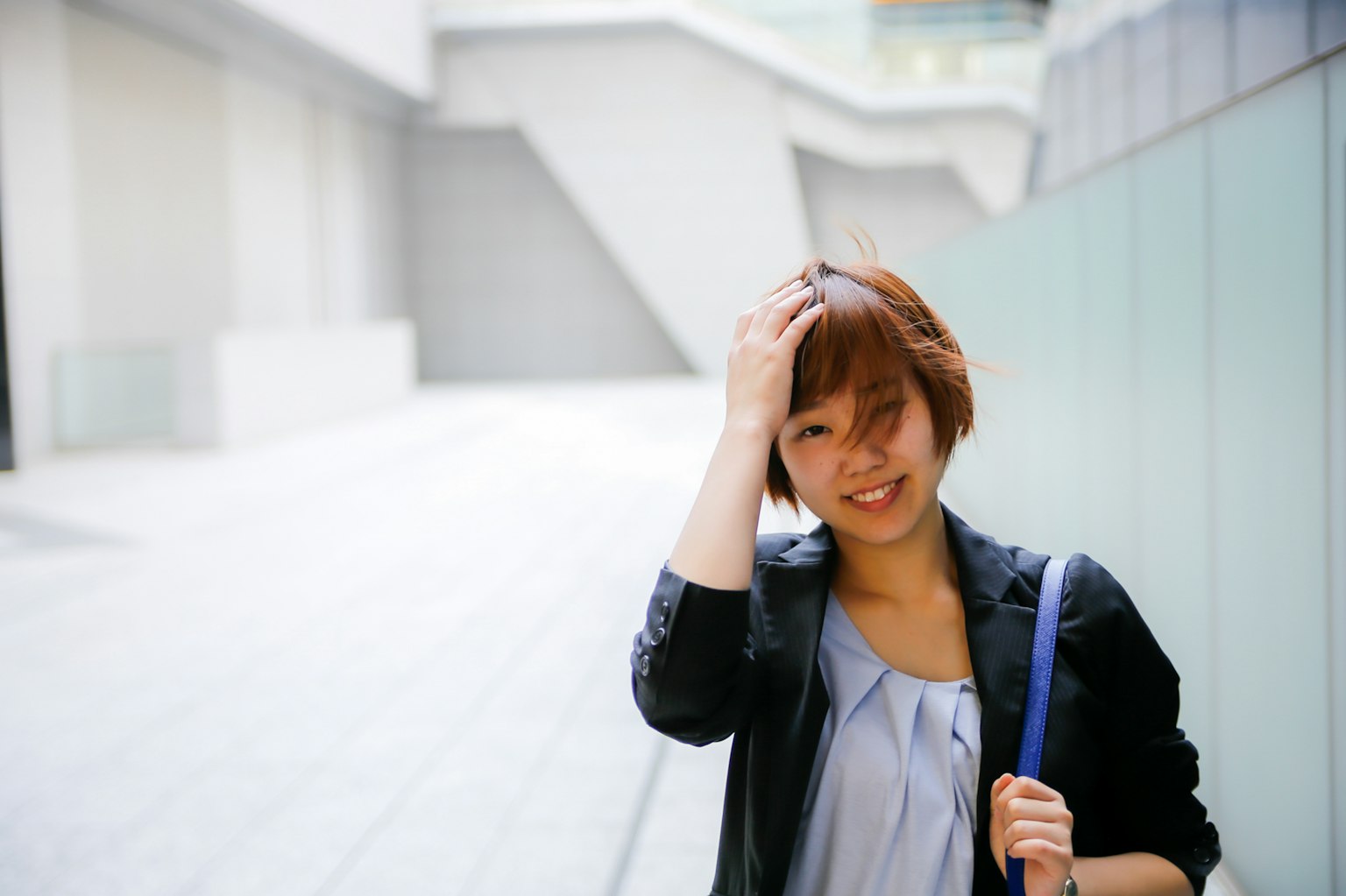 Eine lächelnde Frau, die sich in einer städtischen Umgebung die Haare richtet