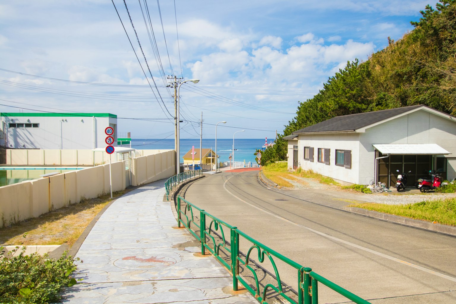 Landschaftsansicht einer Straße, die zum blauen Meer mit einem weißen Haus führt